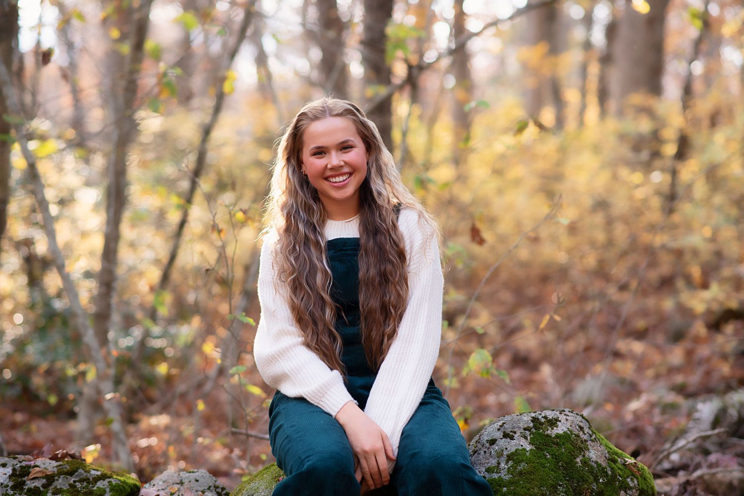 A casual fall portrait outdoors in a wooded area with autumn foliage in the background. Rhode Island Photographer