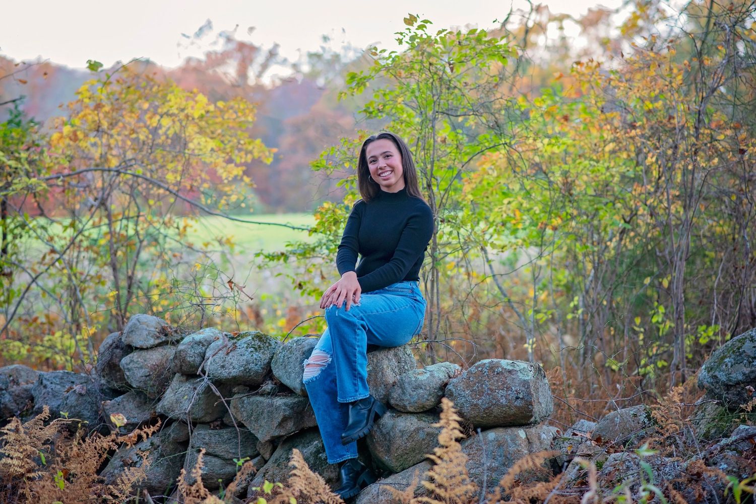 A collection of seven photos showing someone on large rocks in autumn woodland with colorful fall foliage in the background.