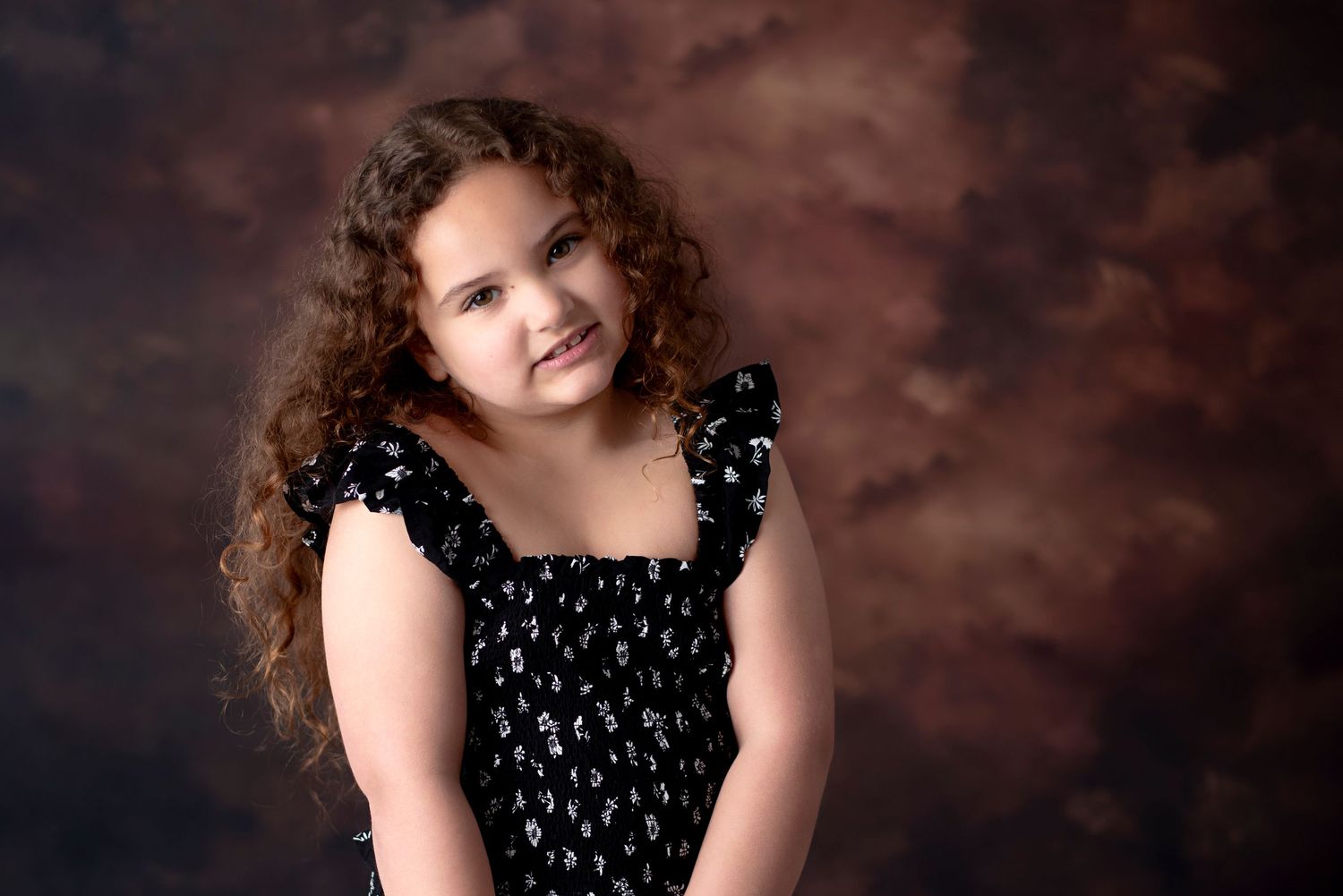 A studio portrait sequence showing curly-haired subject in a dark dress against a brown backdrop.