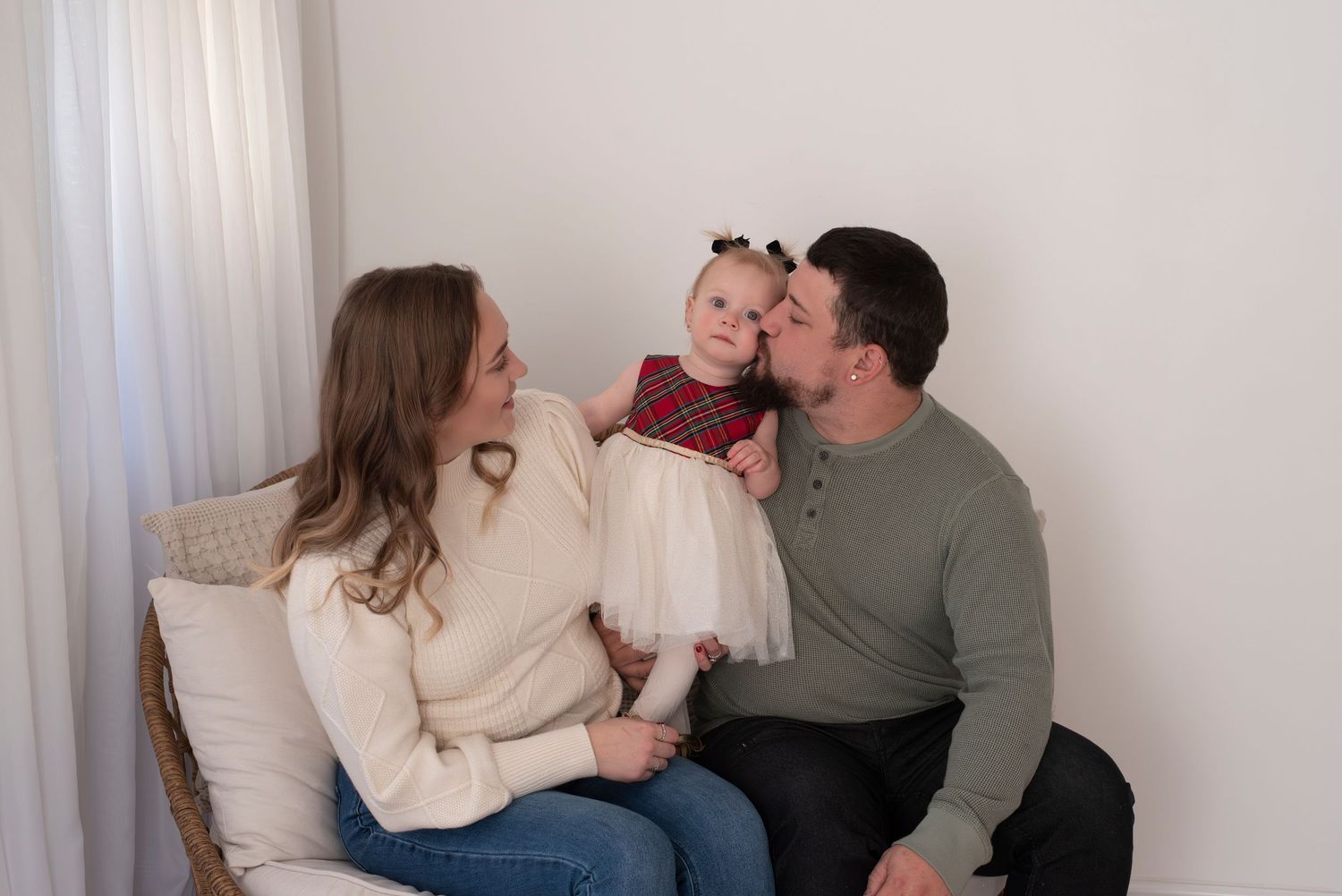 Family spending quality time together on a cozy couch while wearing casual sweaters in a bright room.