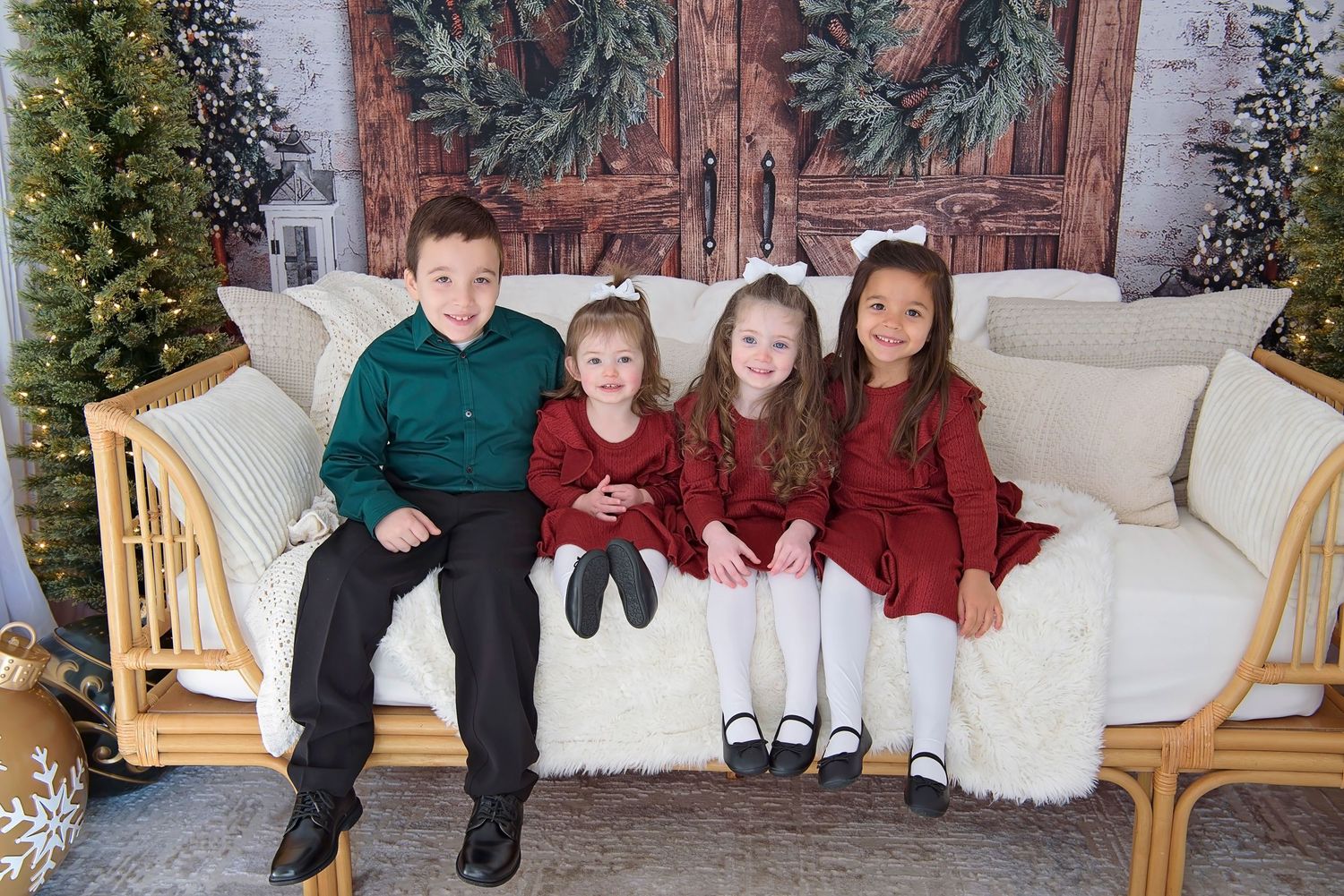 Children gathered on a white couch with holiday decorations and festive red clothing.