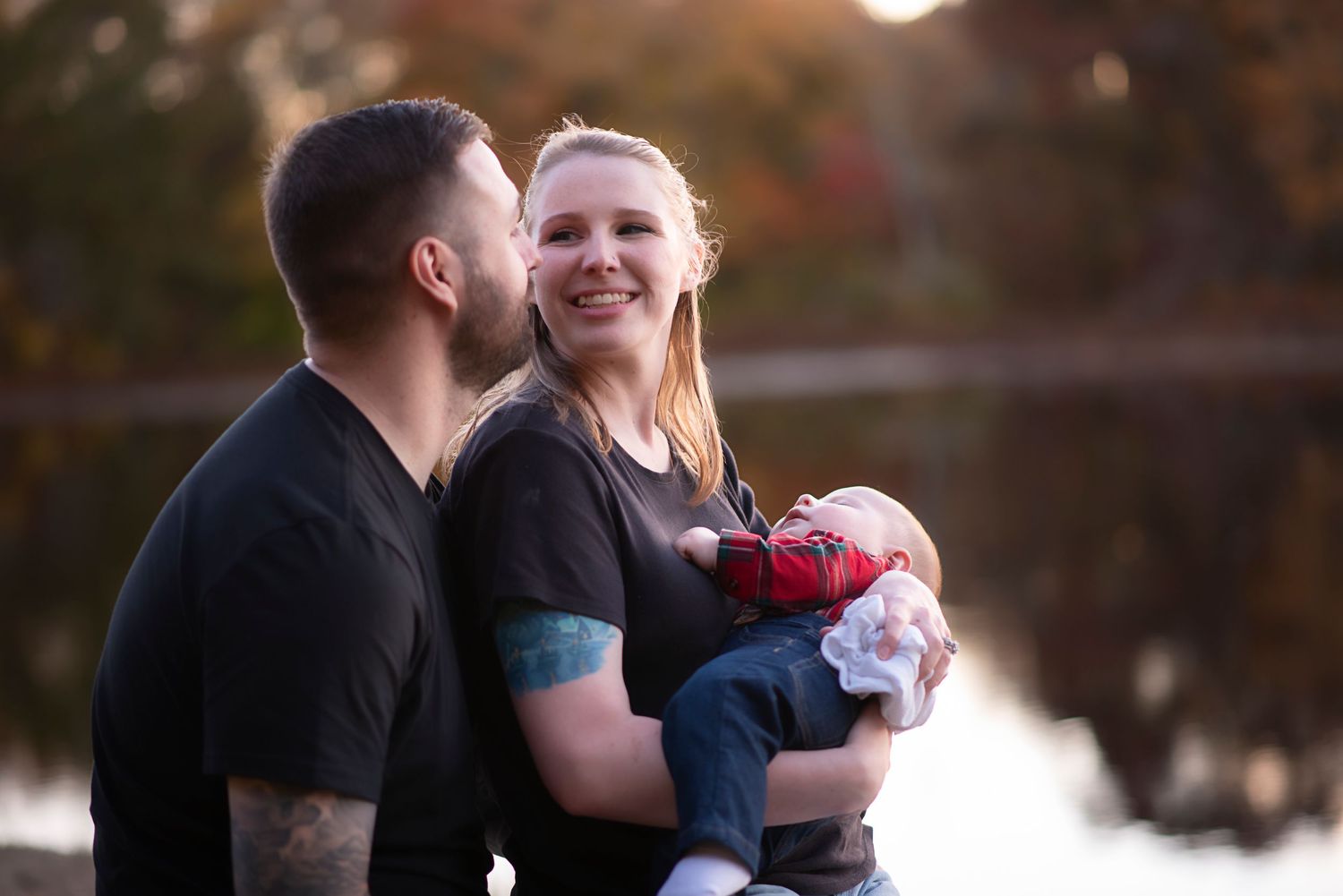Happy couple embraces outdoors in an autumn setting during engagement photo session.