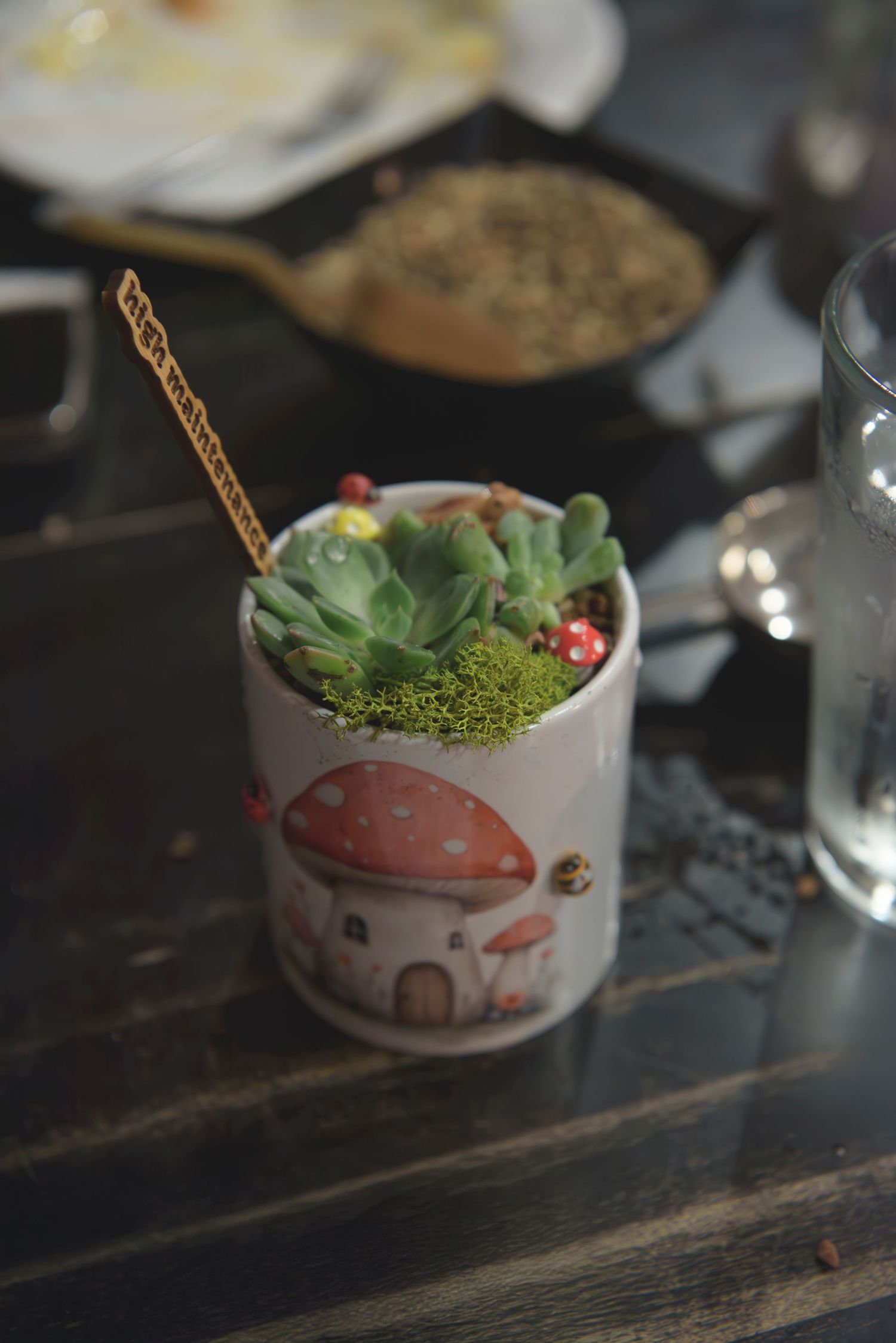 A series of decorative mushroom-themed teacups with green garnishes arranged on a dark wooden surface.
