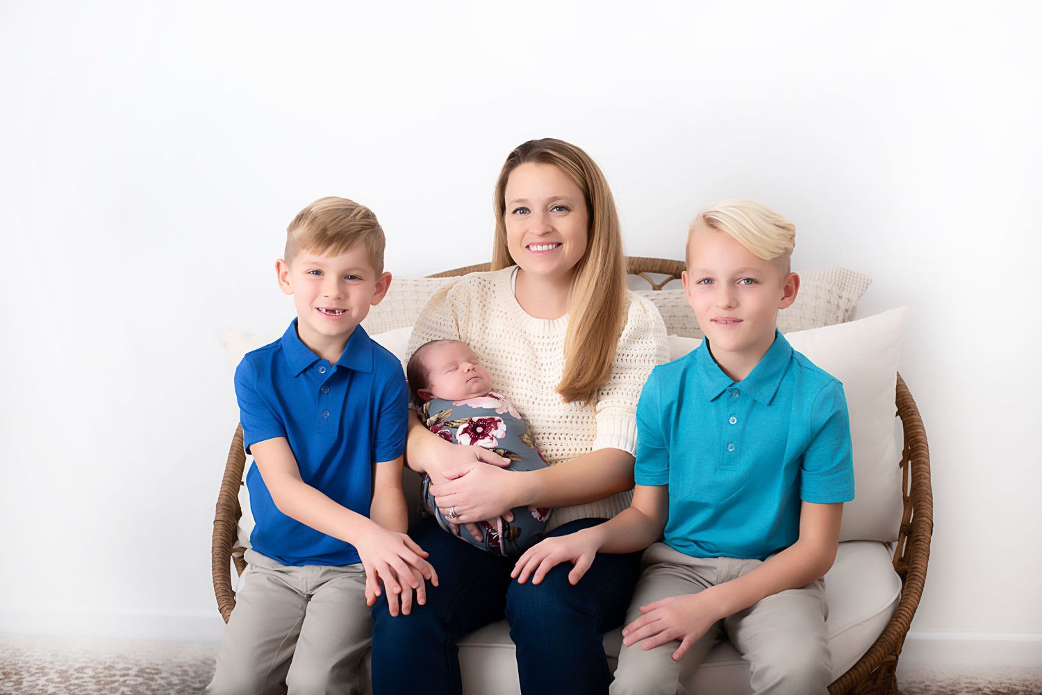A happy family sitting together on a white wicker chair during a studio photoshoot. Rhode Island Photographer