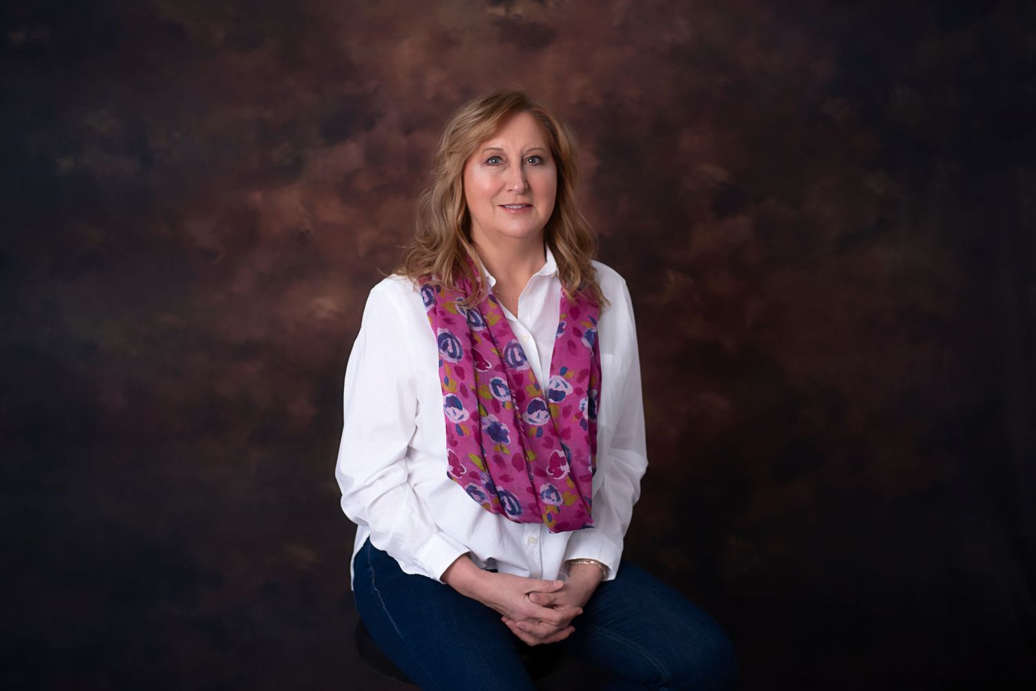 Professional studio portraits against a dark background showing someone in white blouse and pink floral scarf.