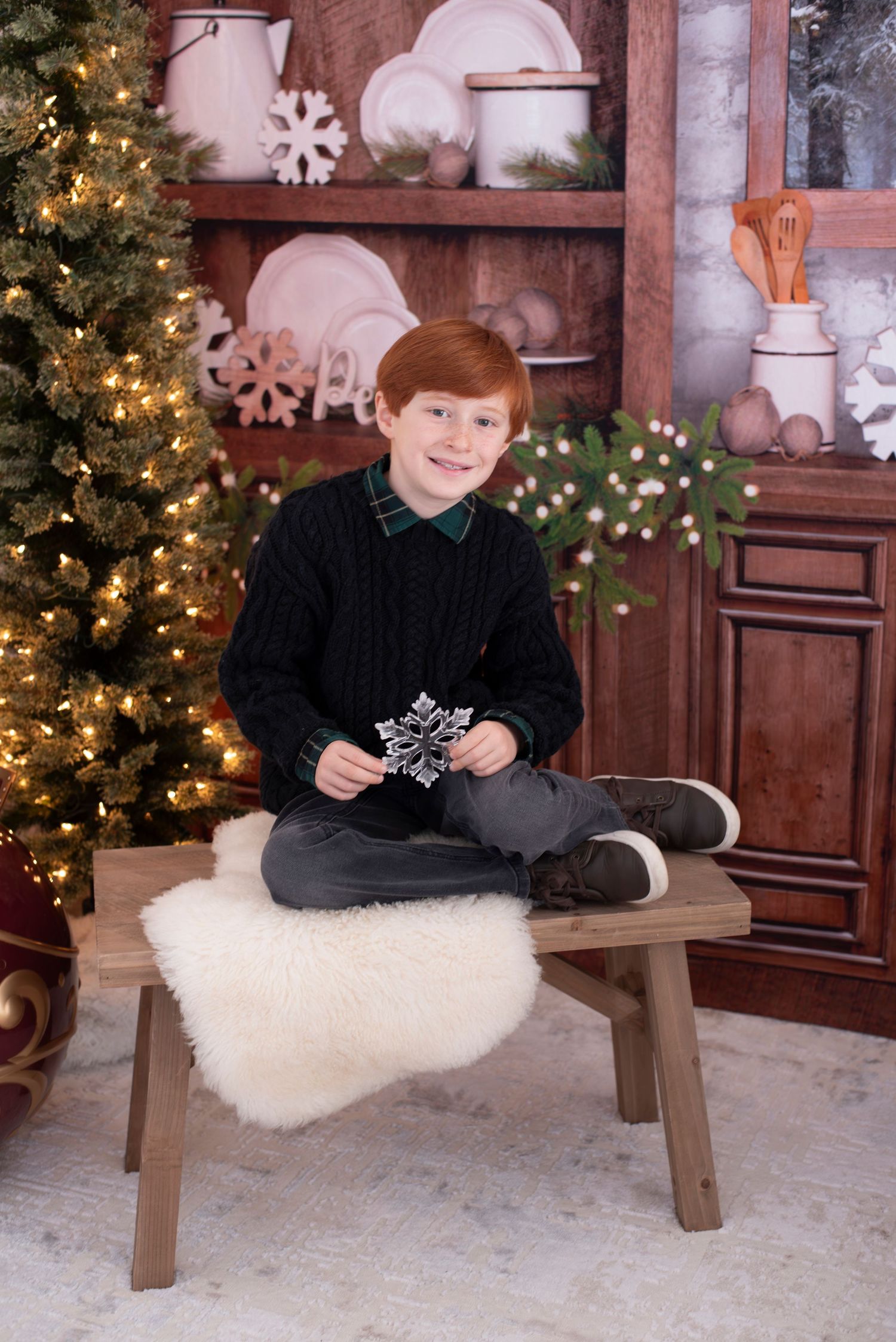 A cozy holiday scene with a wooden bench, decorative snowflakes, and a lit Christmas tree next to a rustic cabinet.
