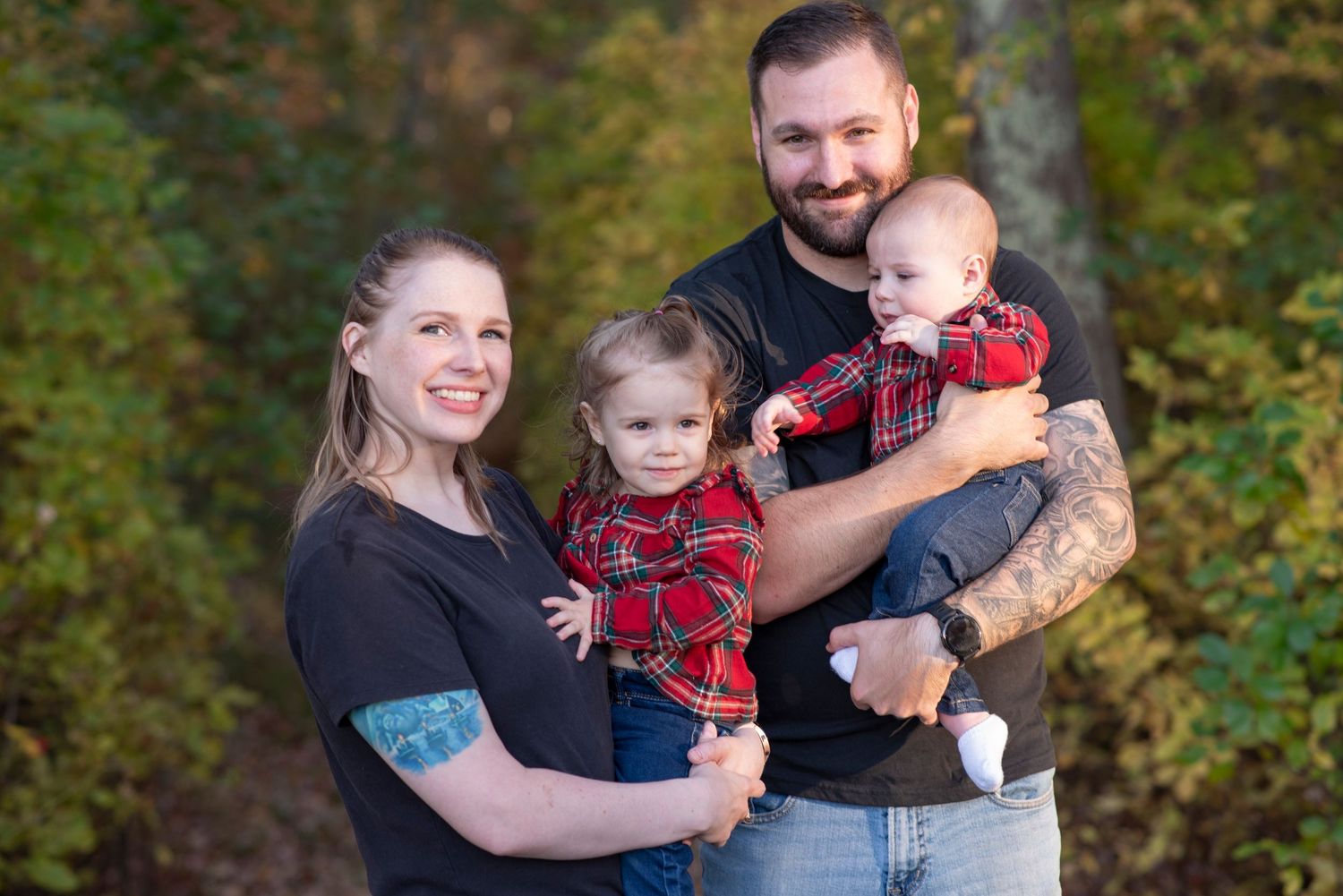 A family shares loving moments in a series of outdoor portraits wearing coordinated red and navy outfits against autumn foliage.