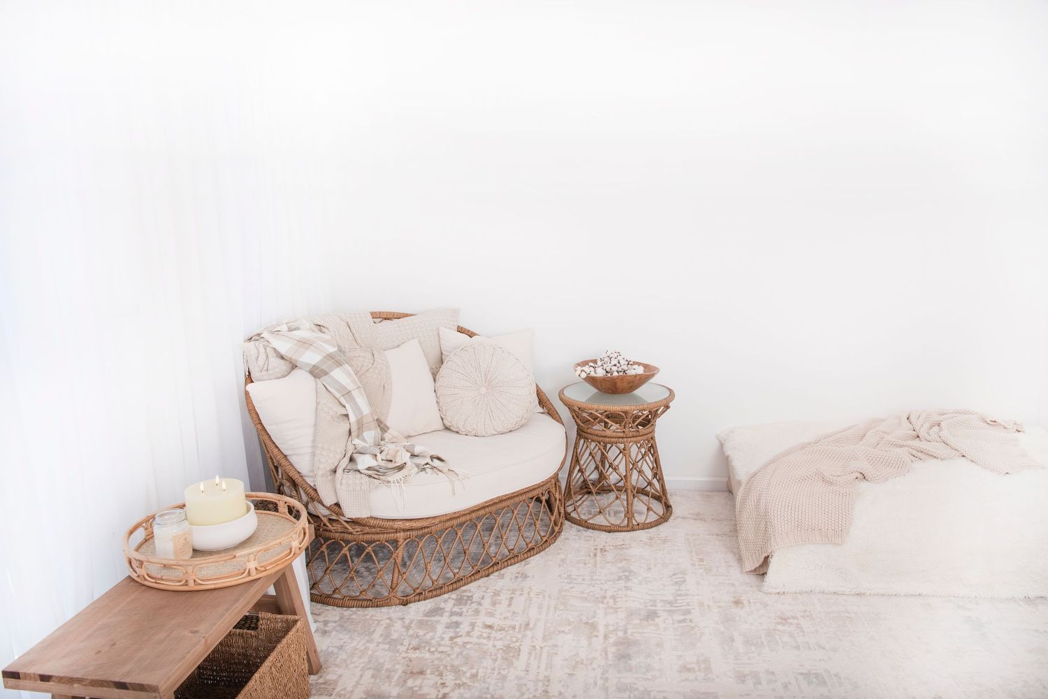 Cozy boho corner with curved sofa, woven side table, and neutral tones on patterned rug. Rhode Island Photographer