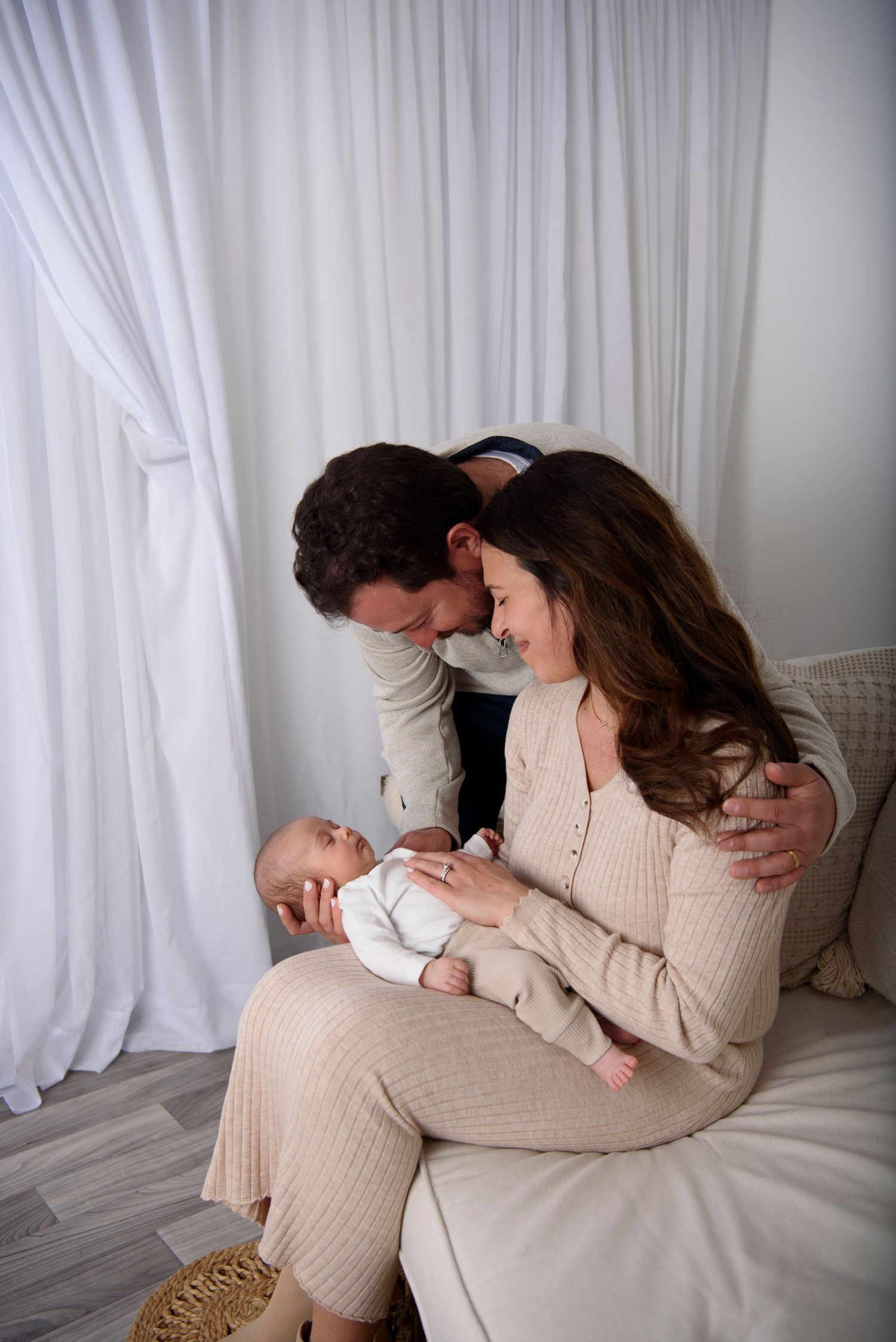 A tender family moment captured in a series of intimate photos against white curtains and light decor.