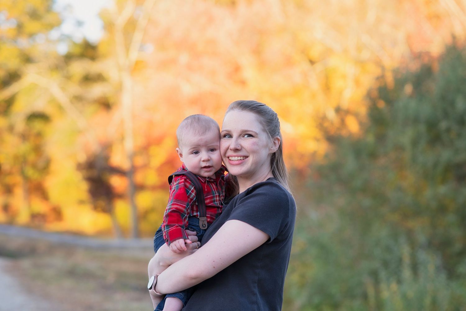 Family enjoying a warm autumn sunset together outdoors with golden light and fall foliage in the background.