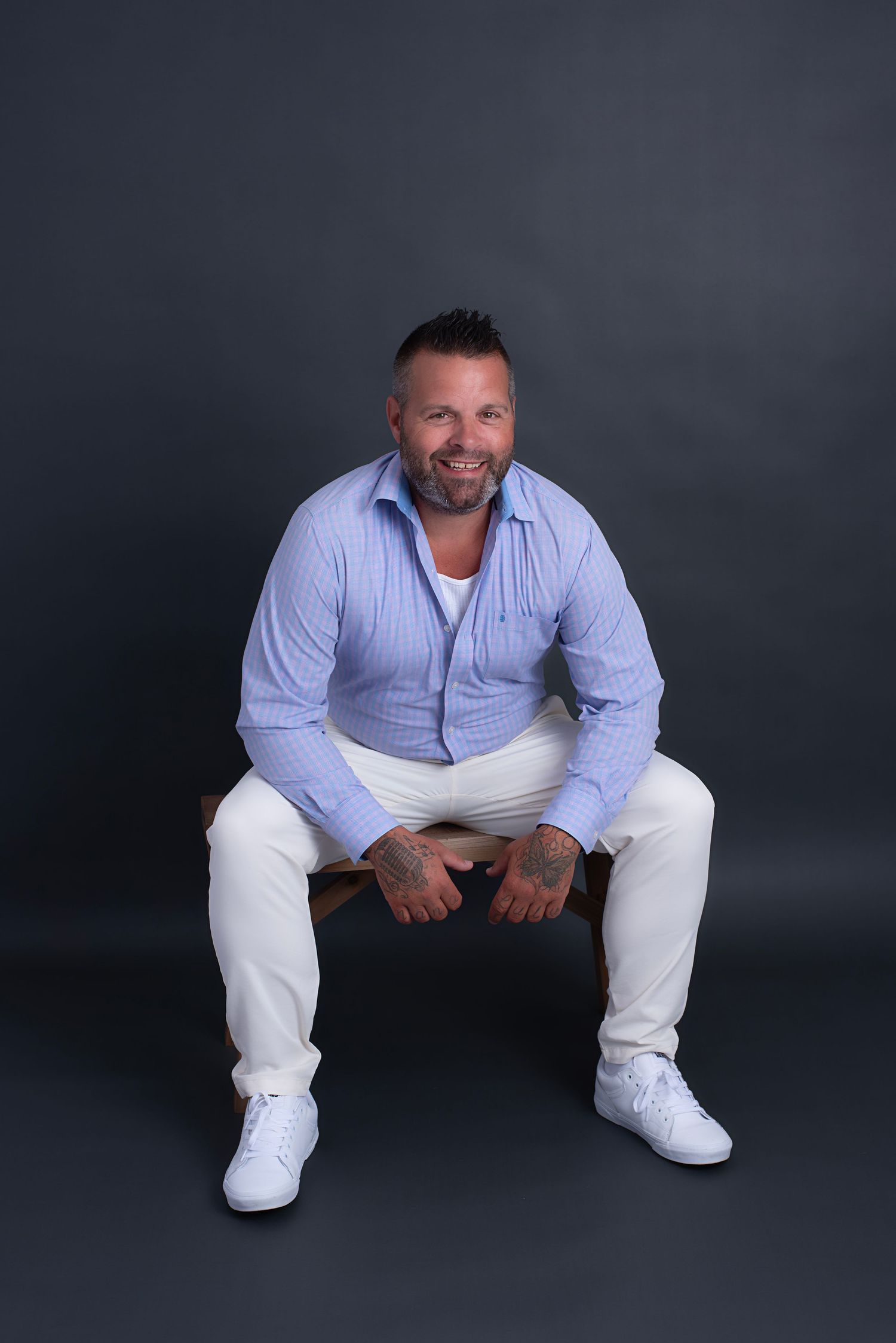 A person in a white light blue button-down shirt and white pants poses against a dark background in a series of shots.