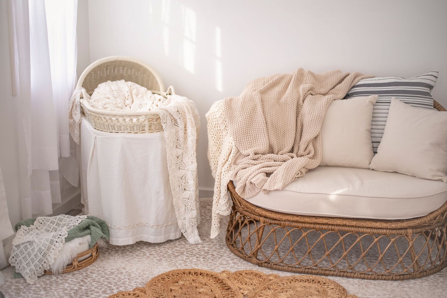 A cozy nursery corner with a wicker bassinet, rattan chair with cushions, and natural decor elements on a textured rug. RI Photographer