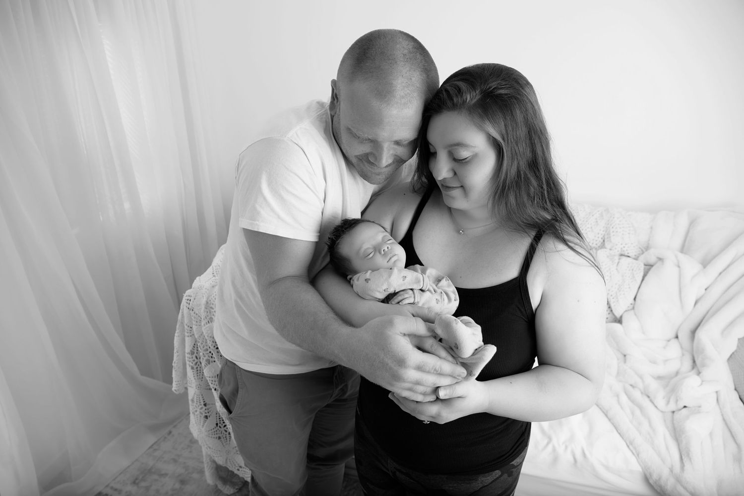 A series of tender black and white intimate moments between two people and a baby against light backgrounds.