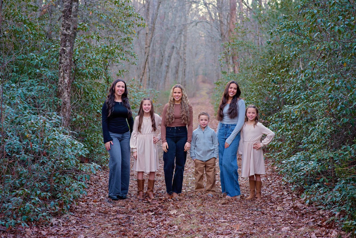 A group of people standing together on a forest path surrounded by green foliage in natural lighting.