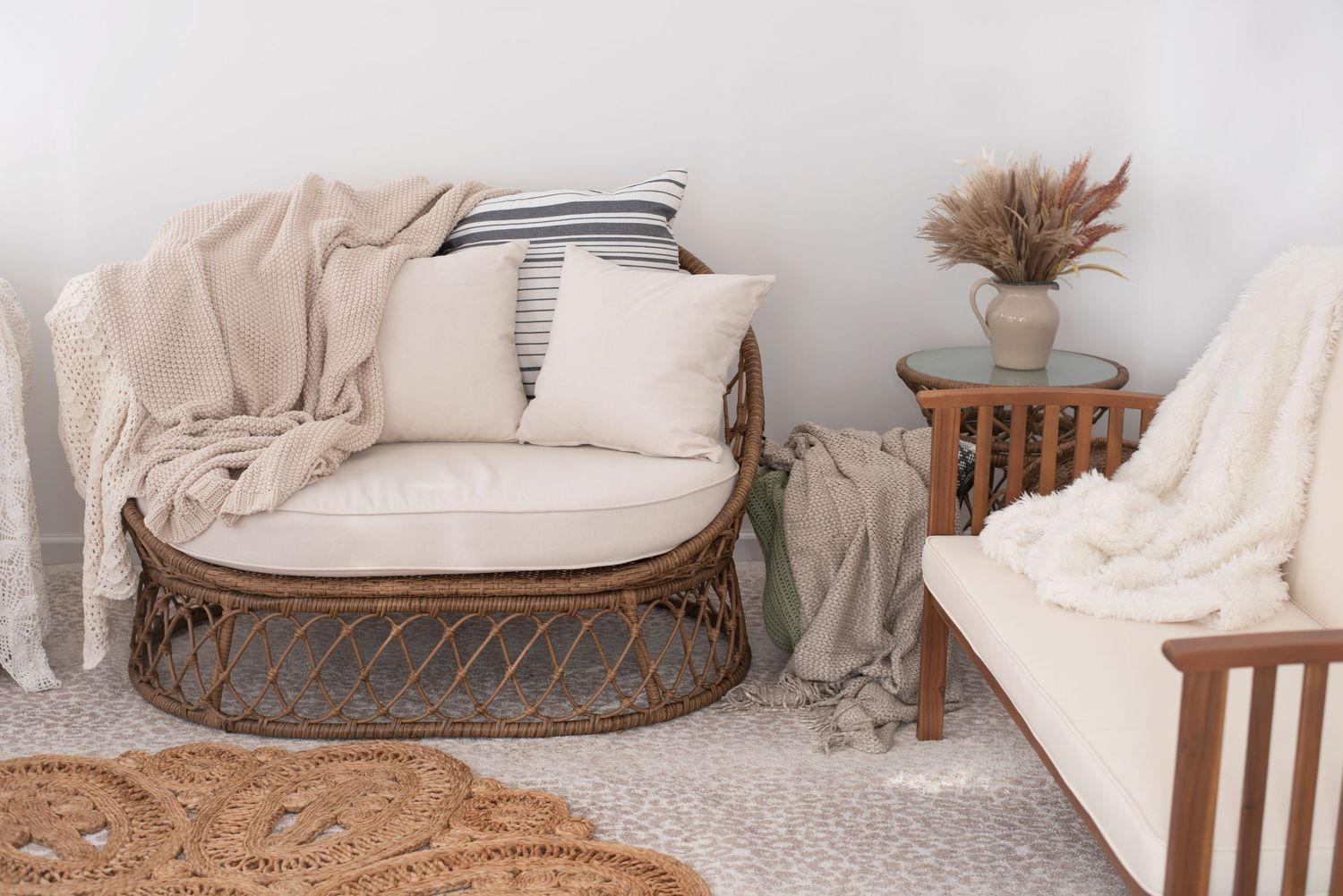 Cozy rattan loveseat with cream cushions, throw blankets and pillows in a minimalist neutral living space. Rhode Island Photographer