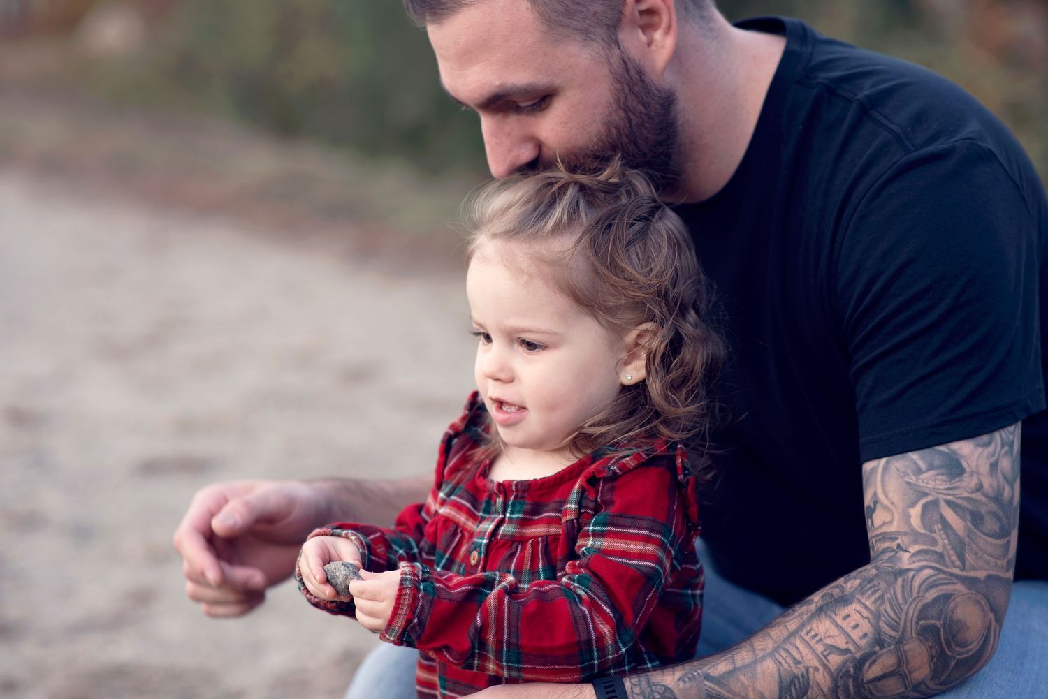 Parent and child share playful moments together while wearing matching red plaid during an outdoor photo session.