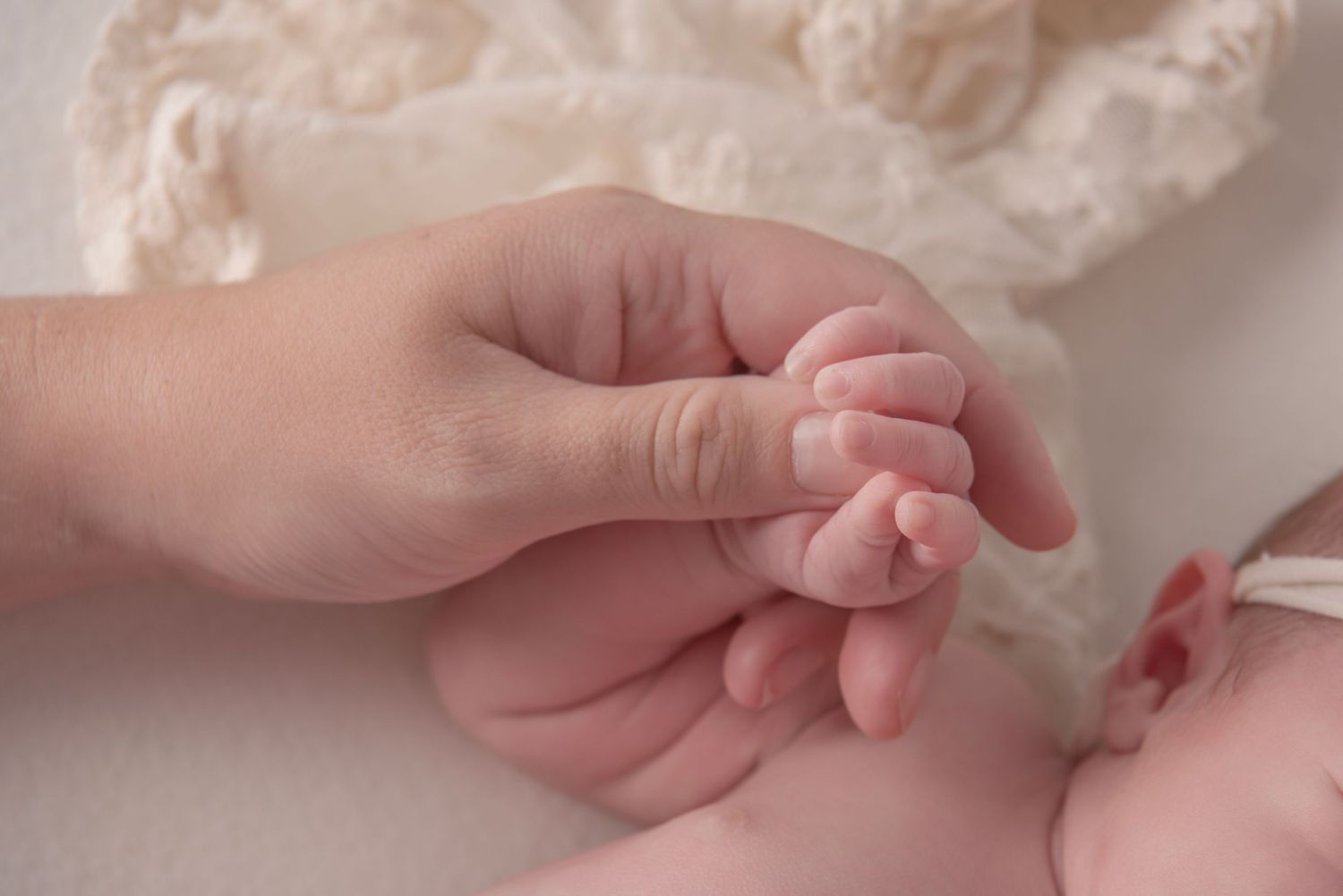 A parent gently holds a newborn baby's tiny hand, showcasing the delicate bond between parent and child.