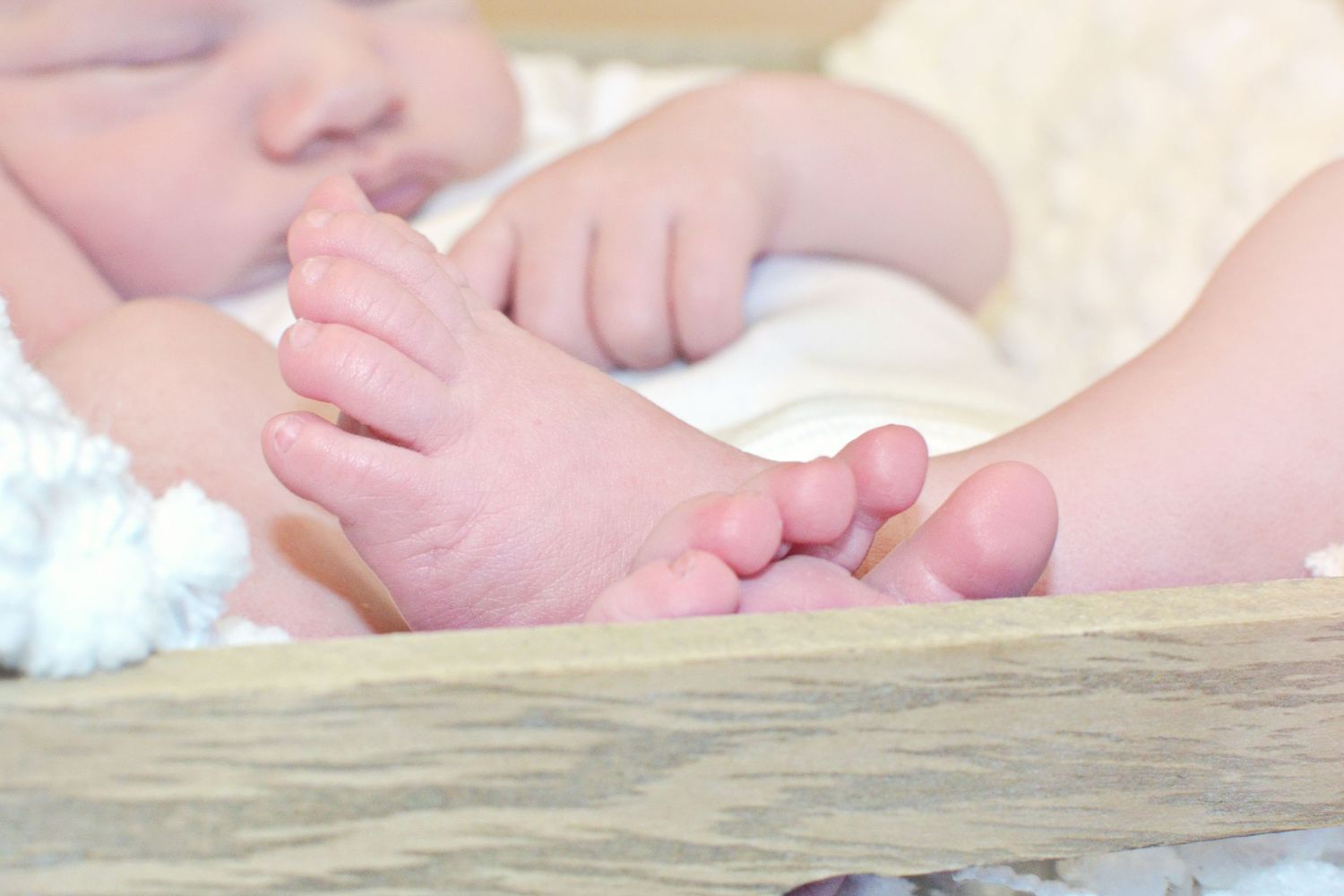 Small baby hand reaching out to touch a wooden surface, showing delicate fingers and tender skin.