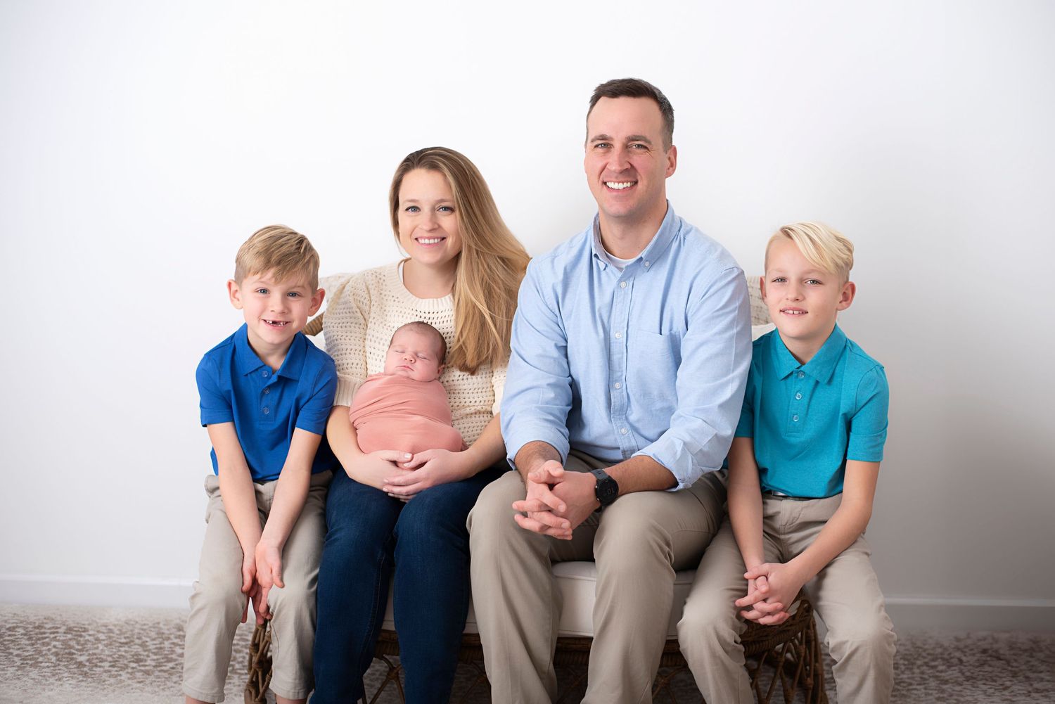 Family of five sits together for a portrait against a light gray background. RI Newborn Photographer