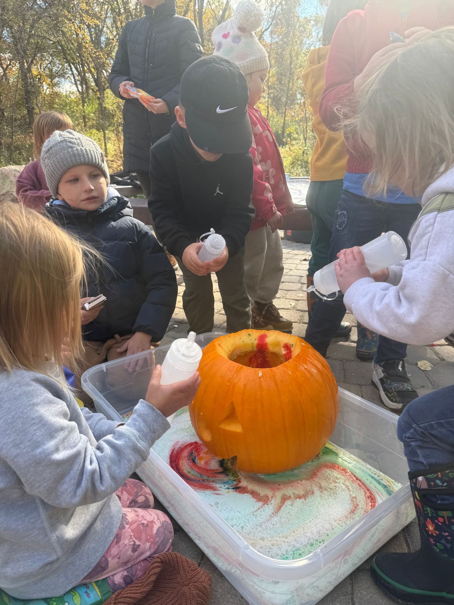 Children cleaned out and carved pumpkins exploring mixing baking soda, vinegar, dish soap, and food coloring to make foam ooze out of face