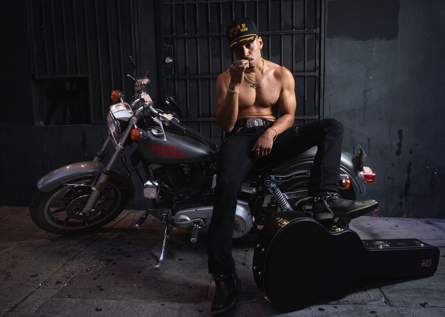 A custom motorcycle with dark paint job and chrome details parked in shadows against a dark background.