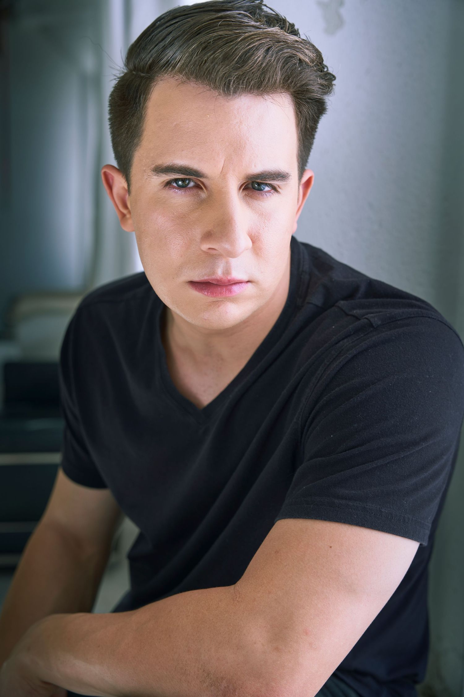 Studio portrait series showing a figure in a black t-shirt captured from different angles in soft natural lighting.