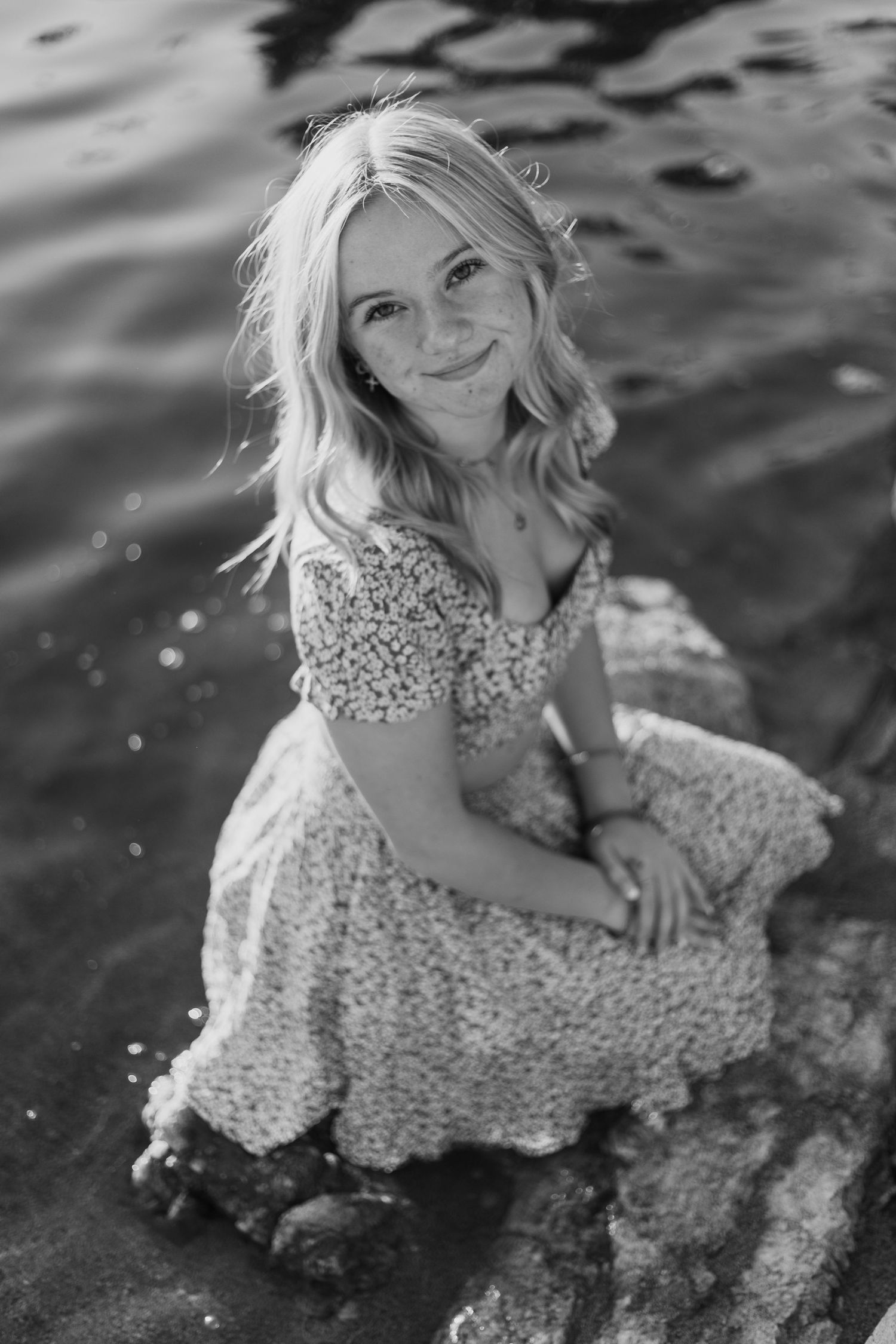 Playful portrait by the water in floral dress with splashing reflections.