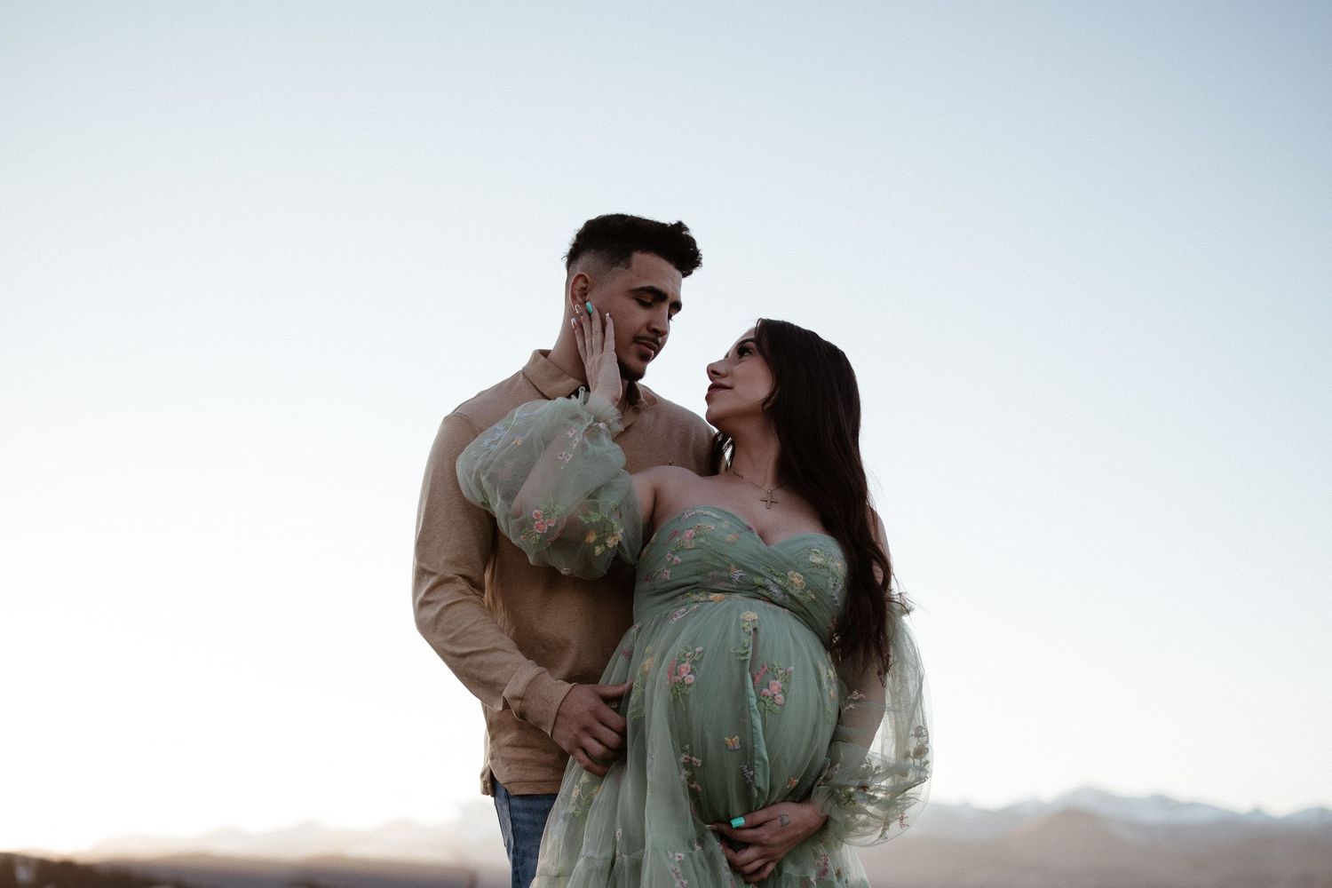 Couple in matching sage green outfits share intimate moments during an outdoor photoshoot at sunset.