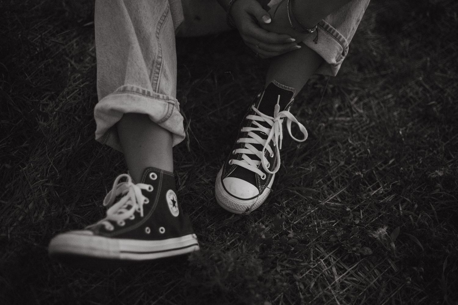 Close-up shots of classic black and white Converse sneakers on dark ground.