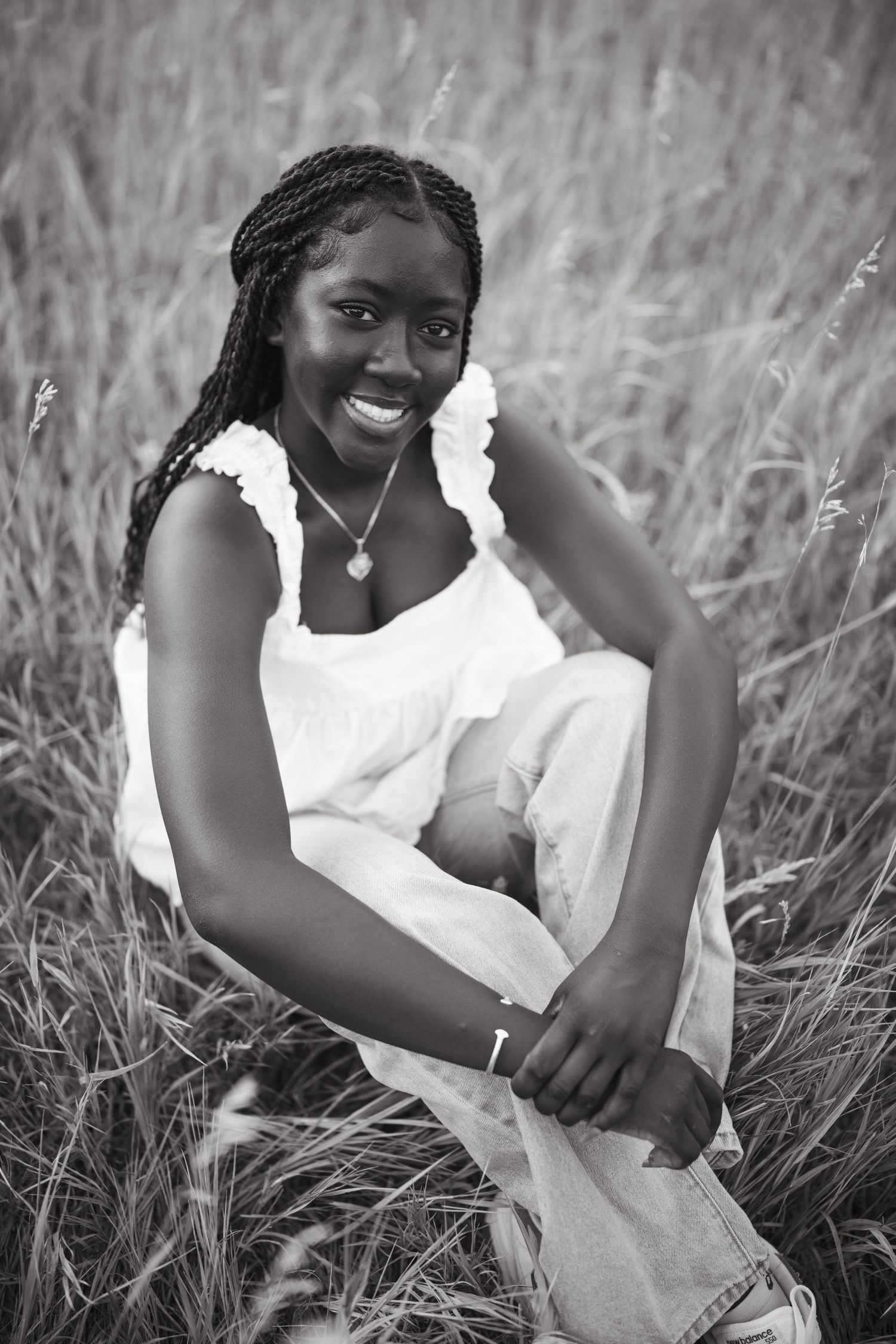 A series of black and white portraits showing someone sitting in tall grass wearing a white dress.