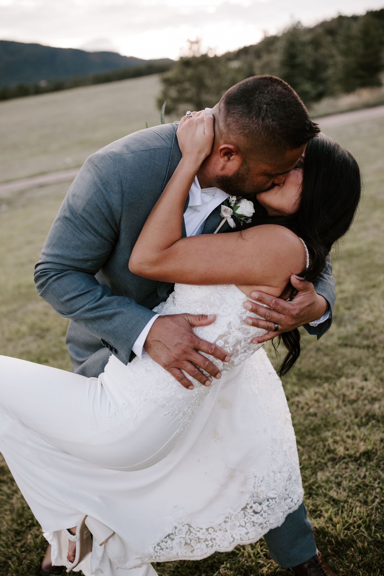 A romantic wedding couple sharing a passionate embrace in an outdoor mountain setting.