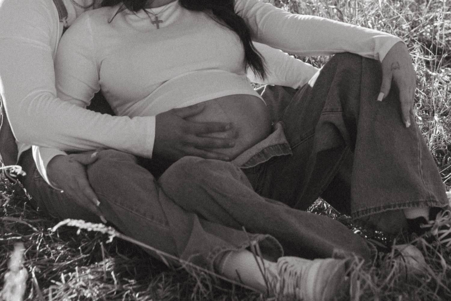 Romantic couple lounging in grass field during outdoor photo session.