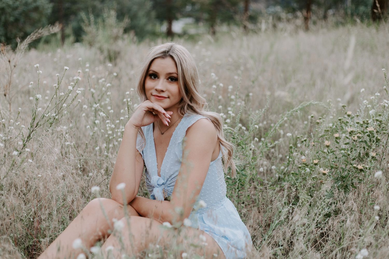 Outdoor portrait in field with soft lighting and light blue summer outfit.