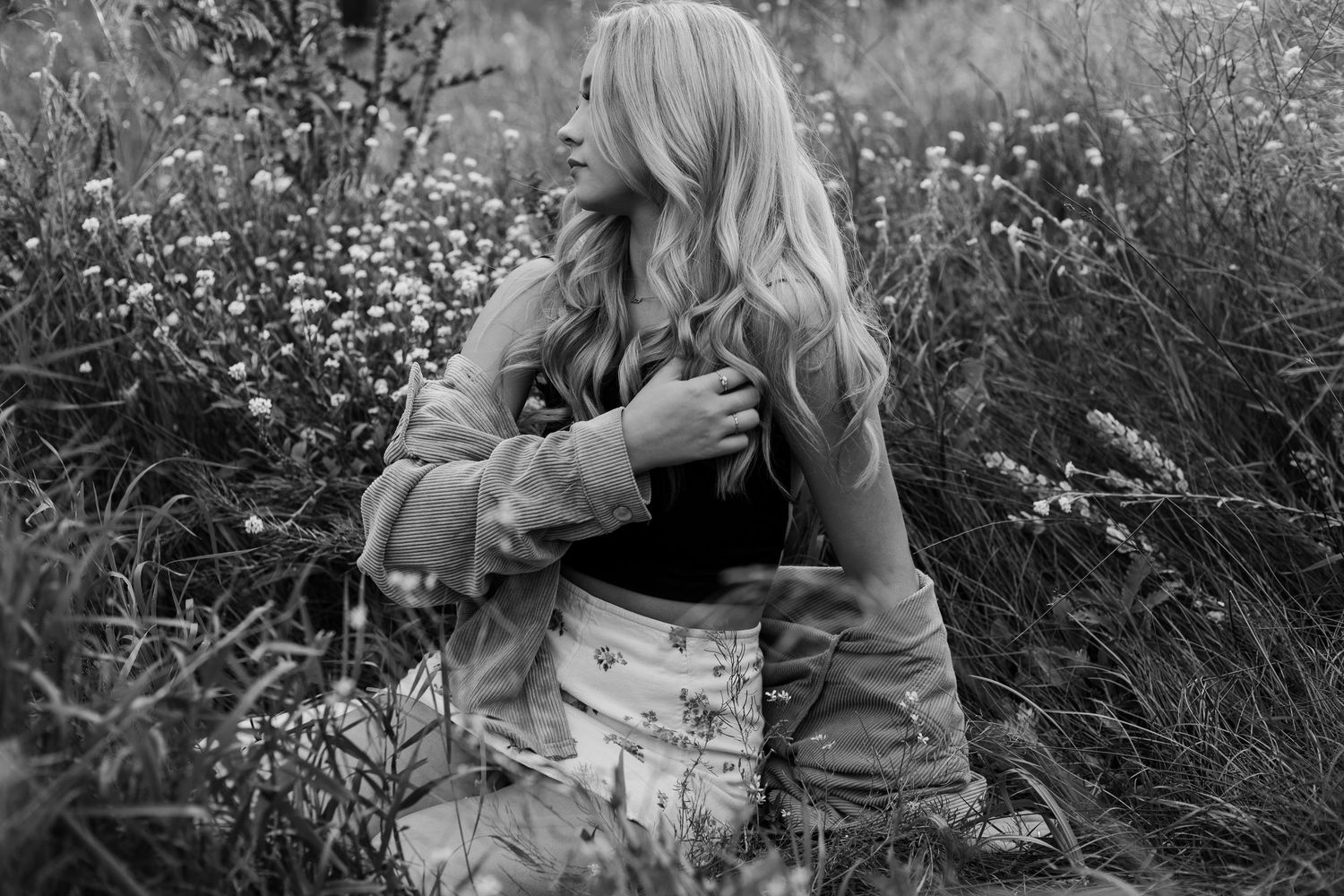 A black and white portrait in a wildflower field with soft lighting and natural surroundings.