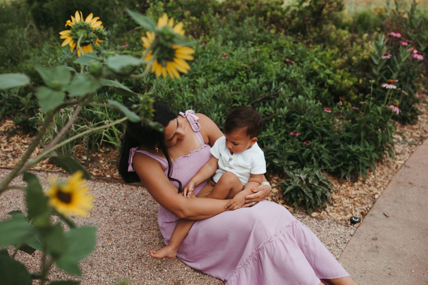 Intimate family moment captured among blooming sunflowers in garden setting.