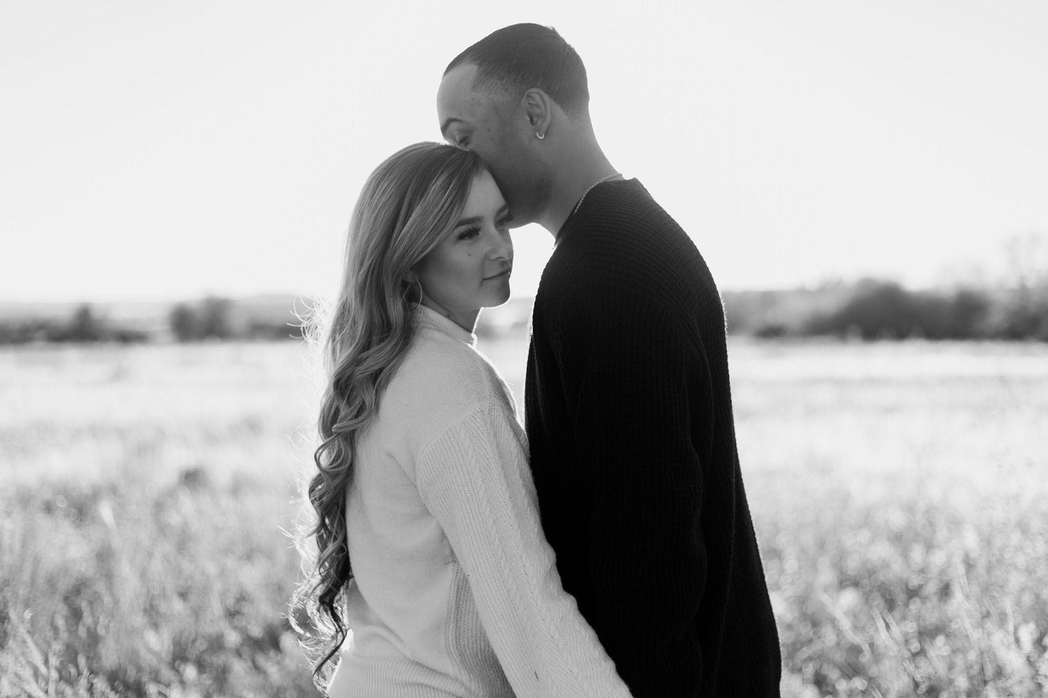 Black and white photograph of a couple in a tender embrace outdoors.