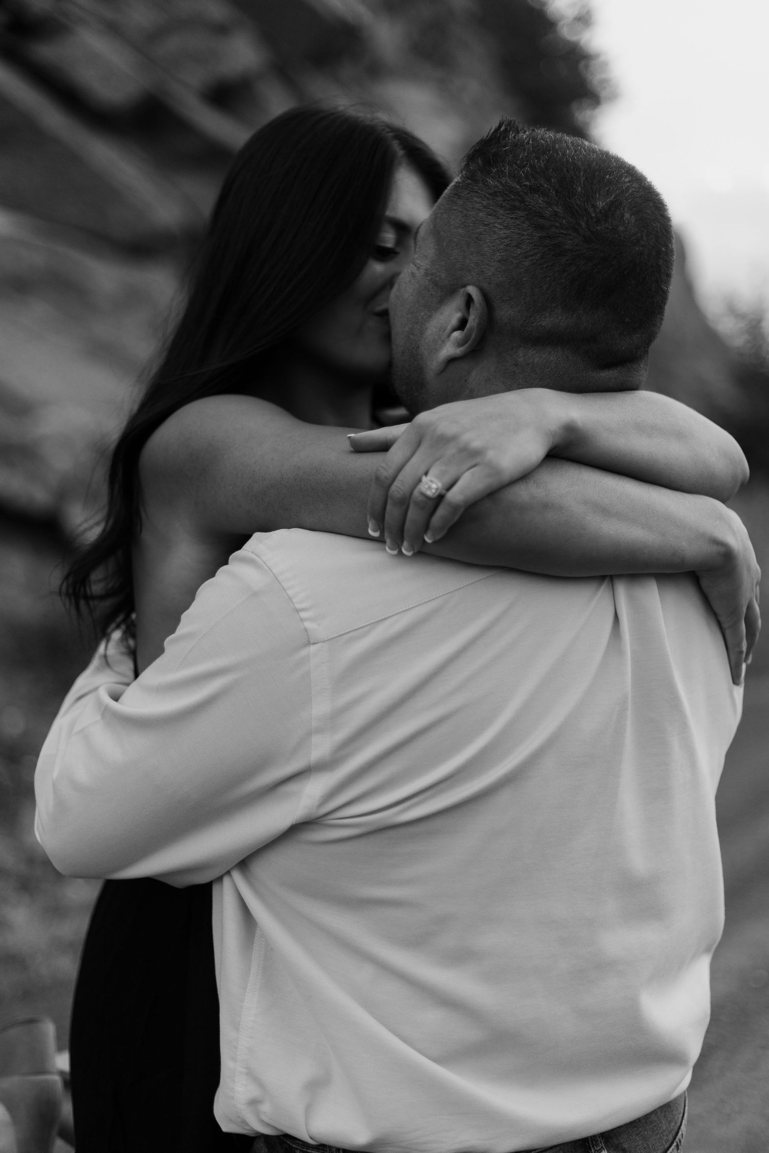 Intimate black and white portrait showing embrace in natural setting.