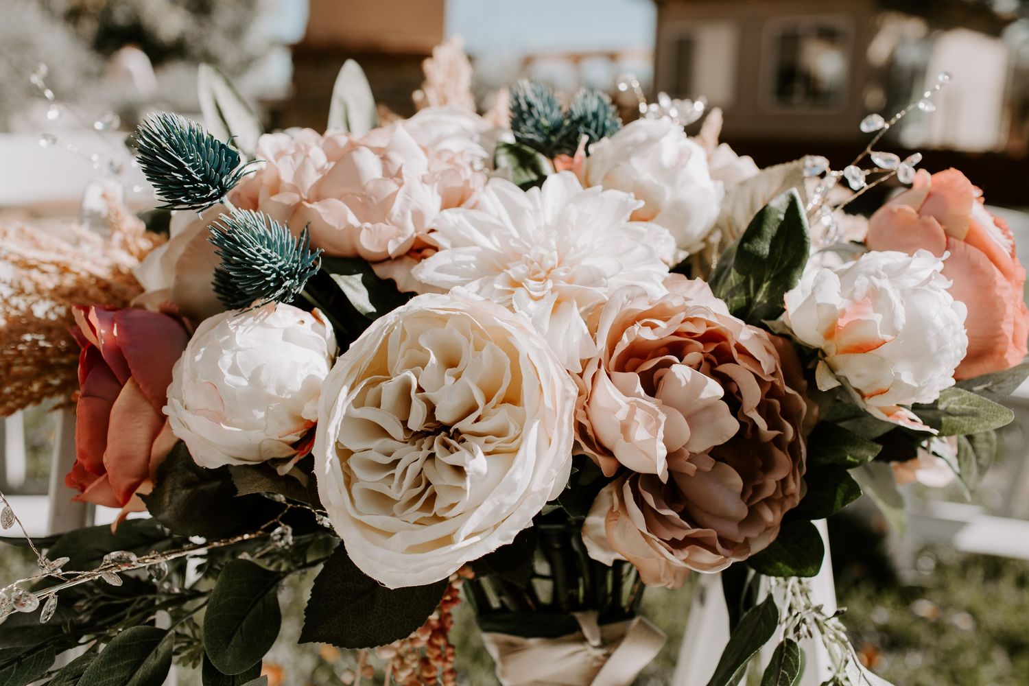 Close-up of romantic peach and blush wedding bouquet with garden roses and greenery.