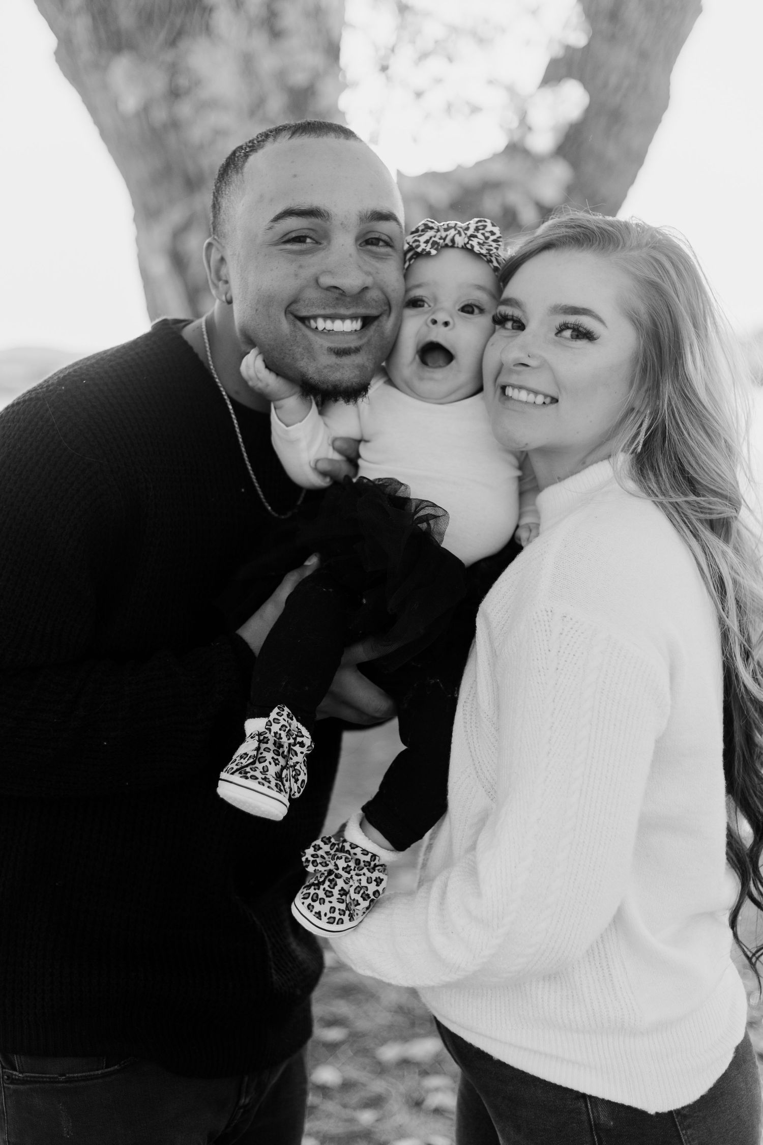 Black and white family portrait showing joyful expressions as they pose together outdoors.