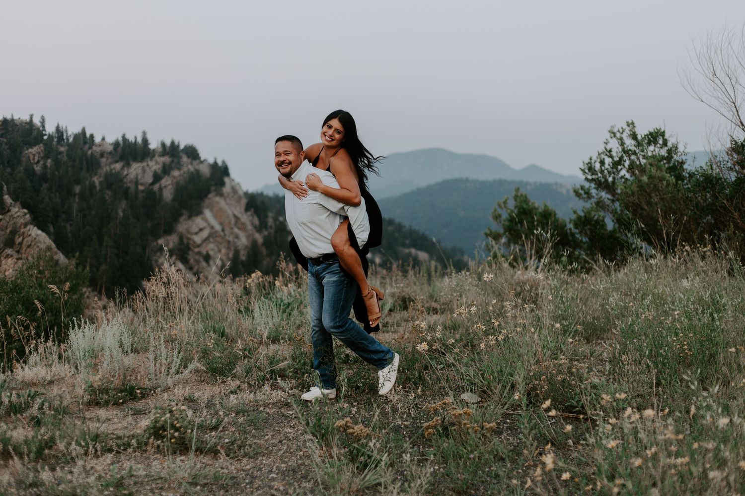 Scenic mountain landscape shot with couple walking through wildflower field.