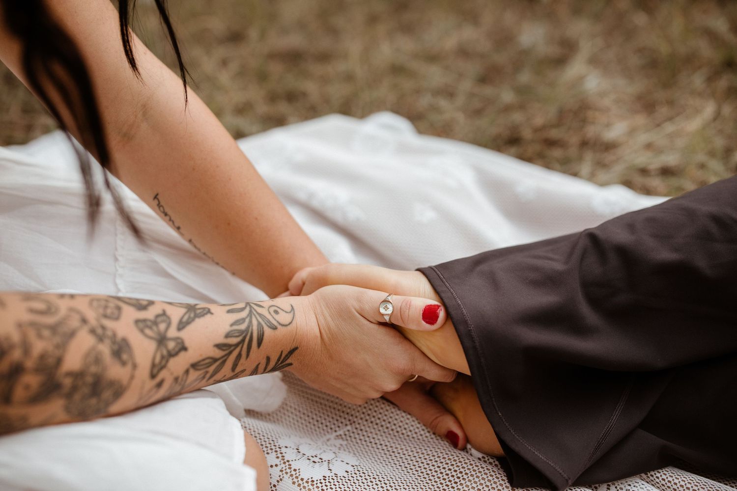 Hands with red nail polish carefully fold and prepare dark clothing with delicate white lace details.