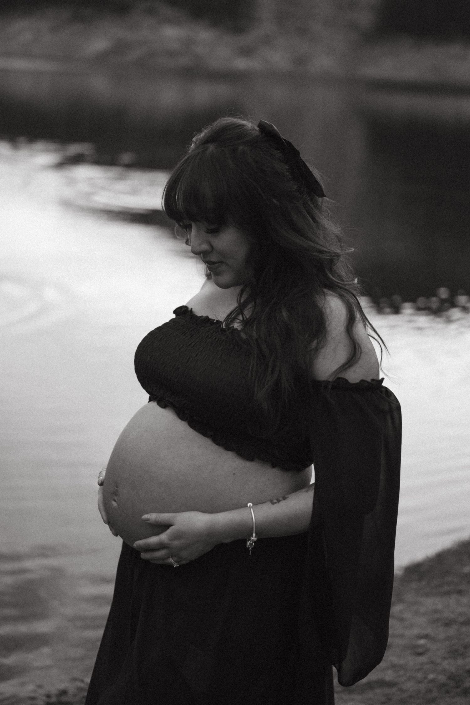 A series of black and white photos showing two people embracing in silhouette by a waterfront.