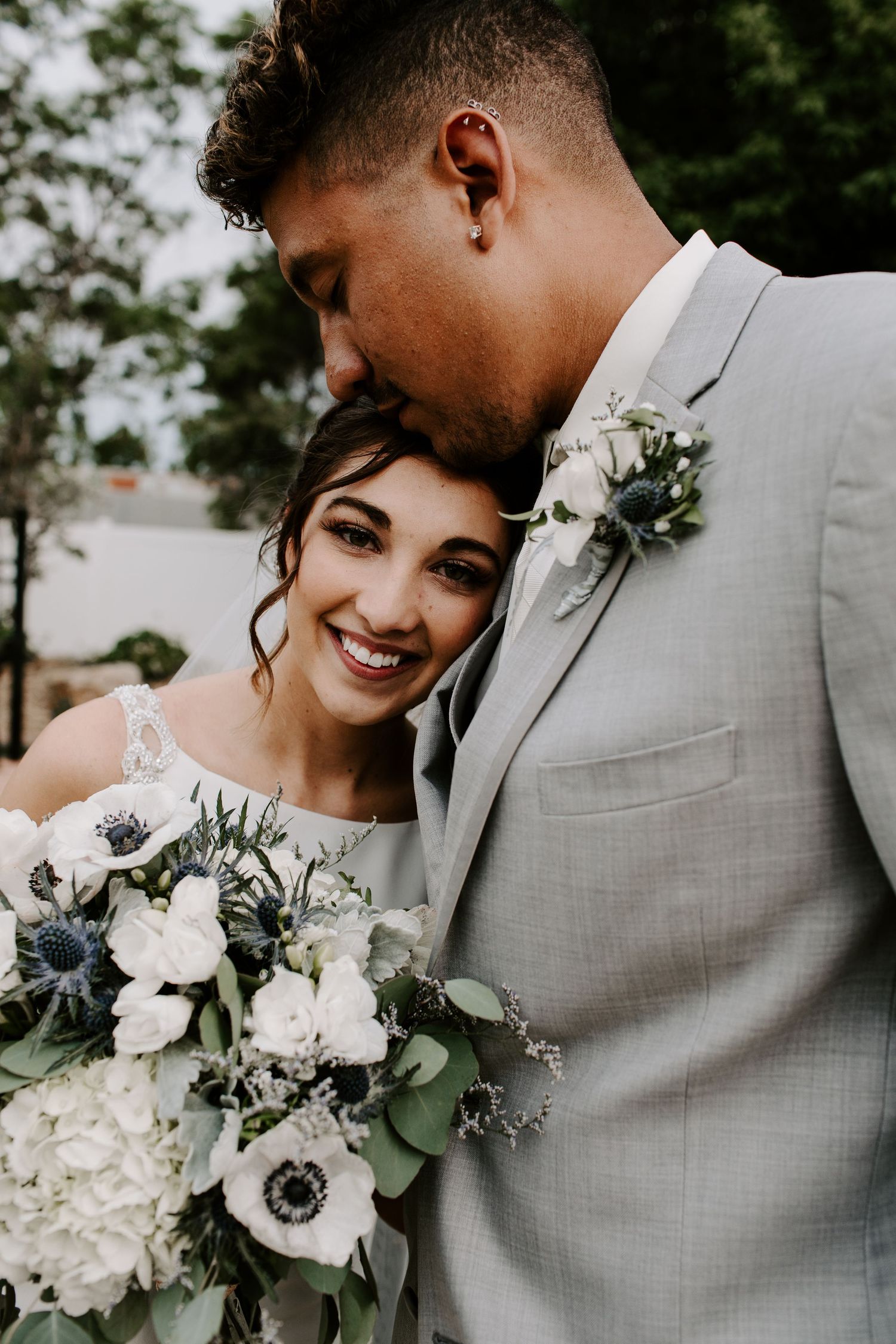 Close-up wedding photos with beautiful white floral bouquet and grey suit details.