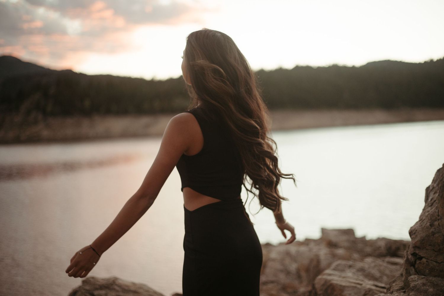 Silhouettes against a sunset sky near a serene lake.