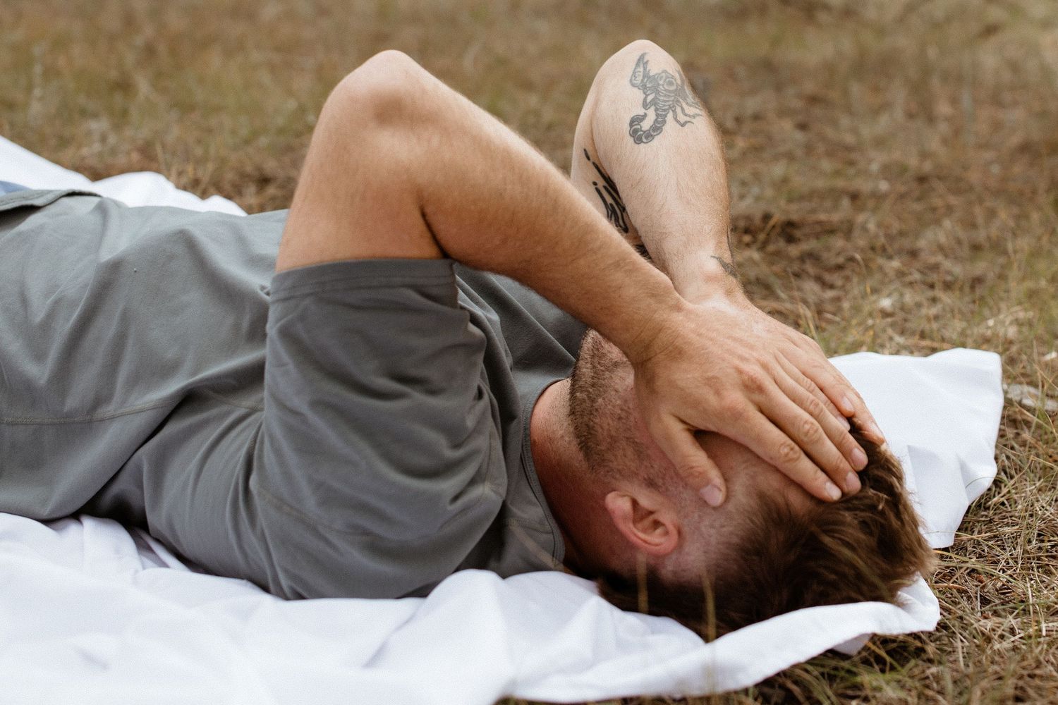 Artistic portrait of someone lying on white fabric in a field.