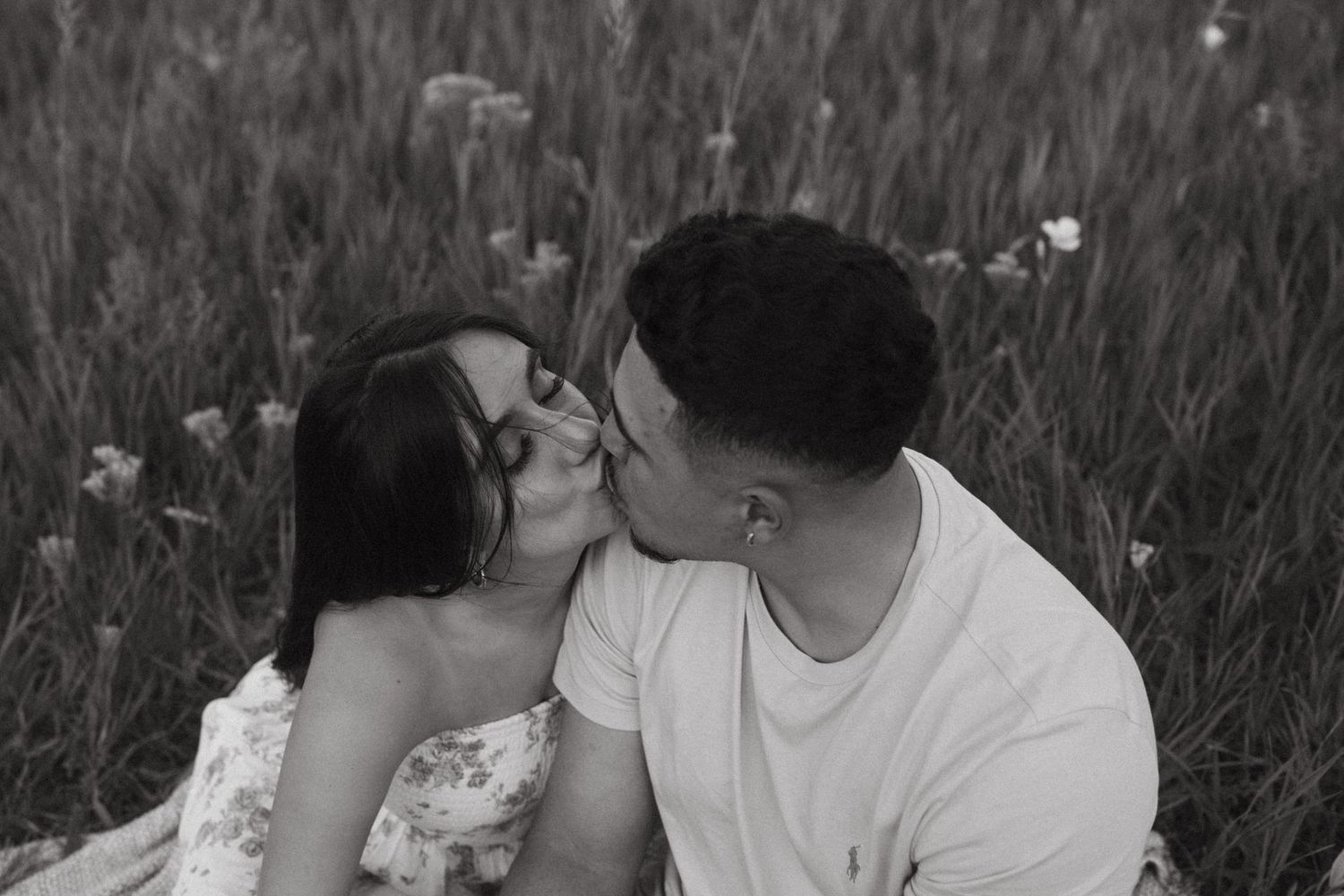 Black and white photo of a couple enjoying an intimate moment outdoors.