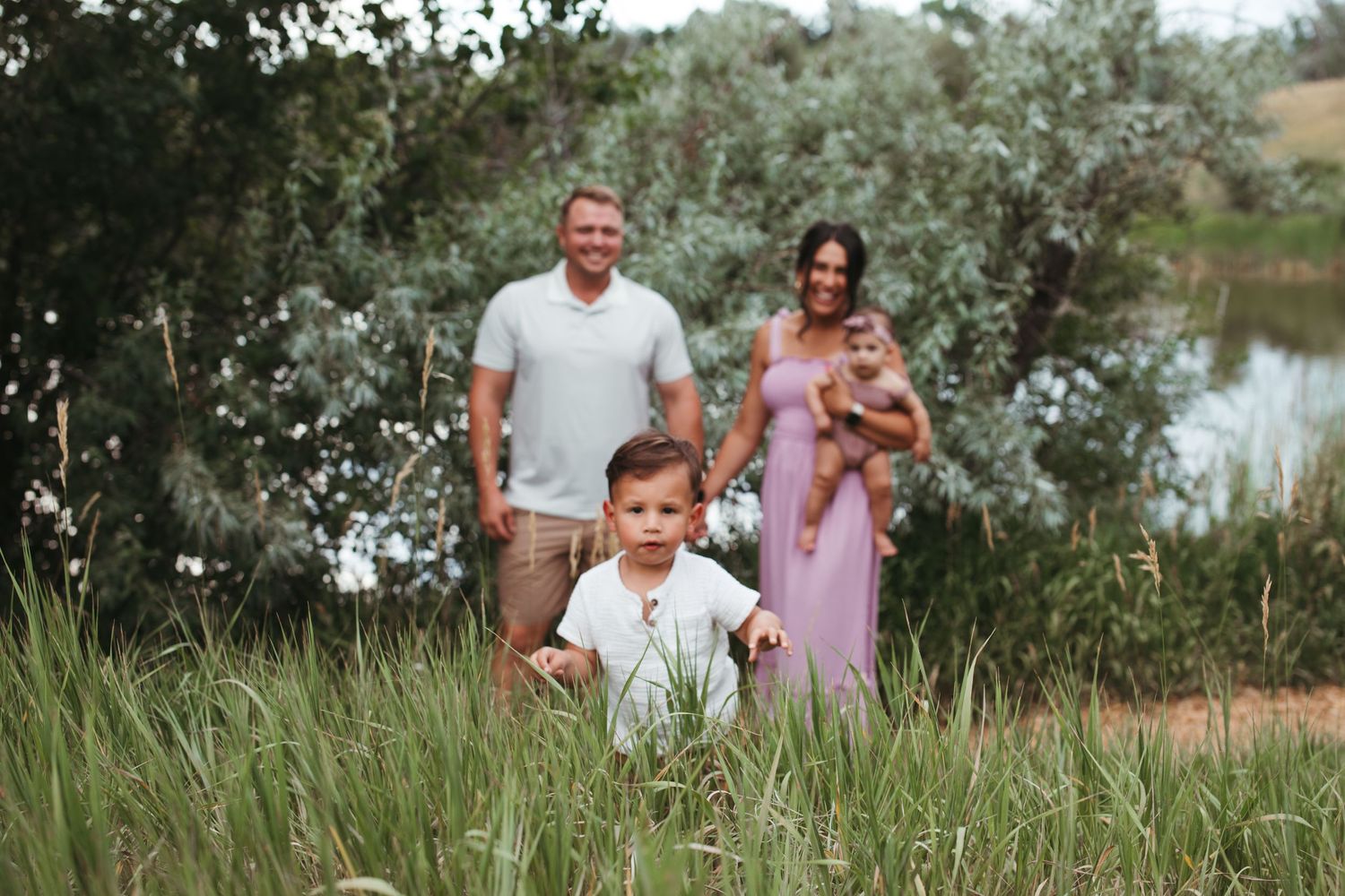 Family enjoying a playful moment together in a lush green field during summer.