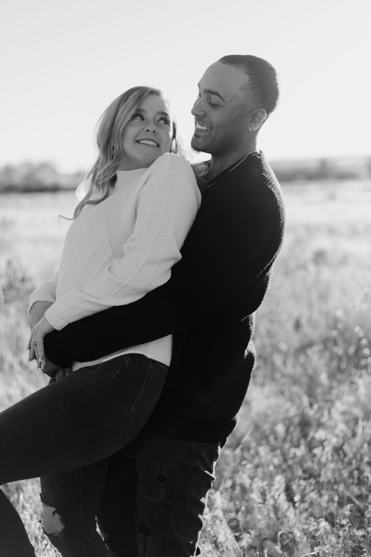Joyful couple sharing a laugh during black and white outdoor photoshoot.