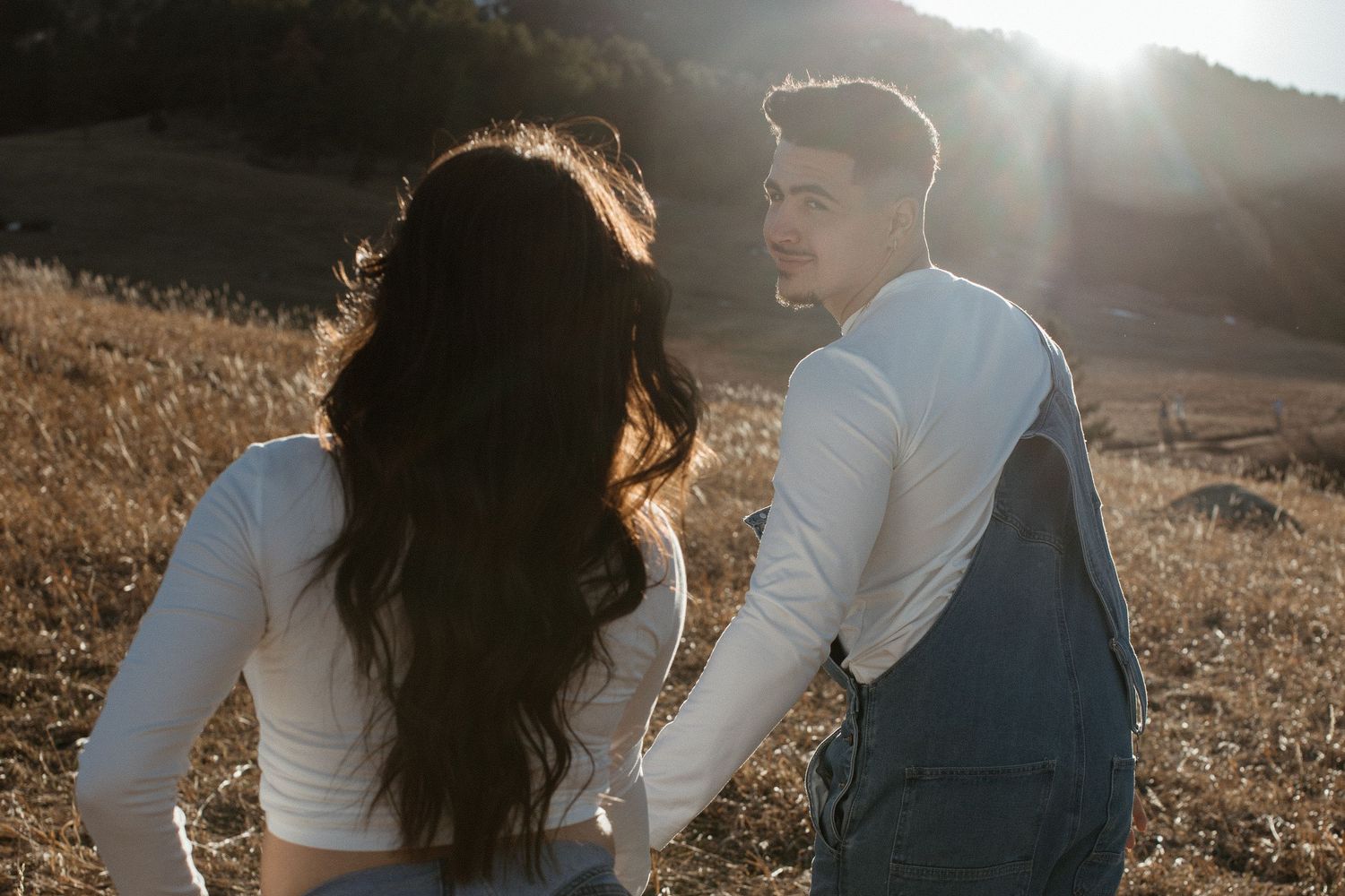 Golden hour couples photoshoot with dramatic mountain backdrop and lens flare.