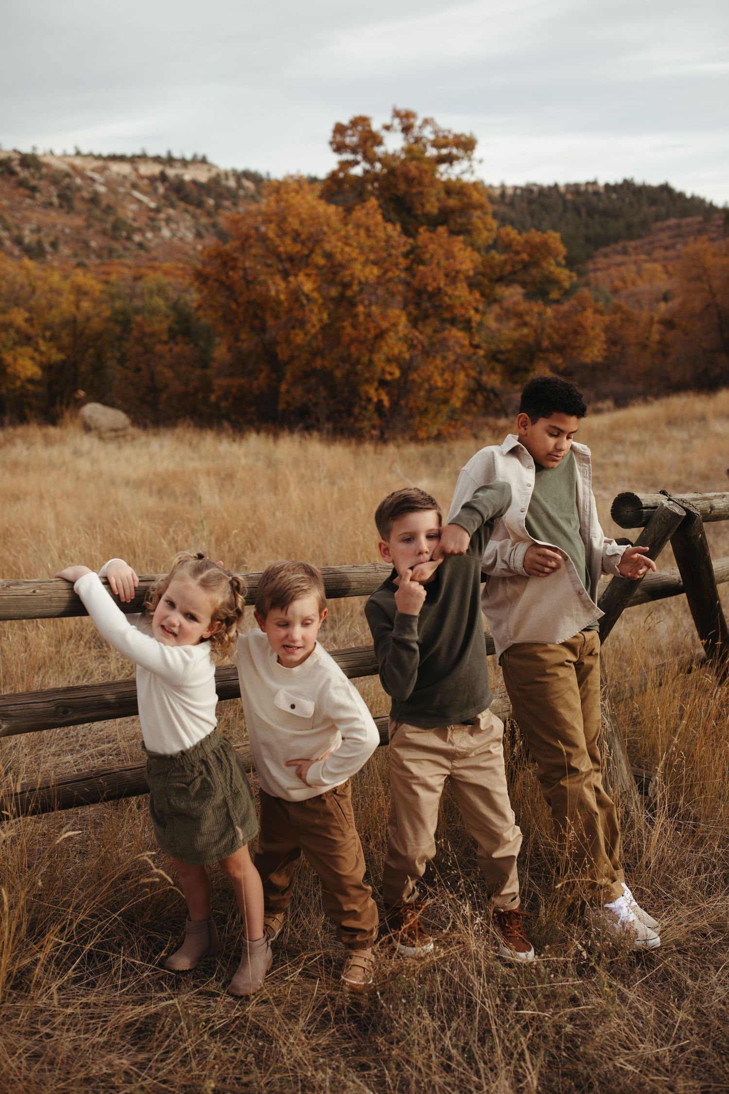 Playful group poses in line through autumn field during sunset photoshoot.